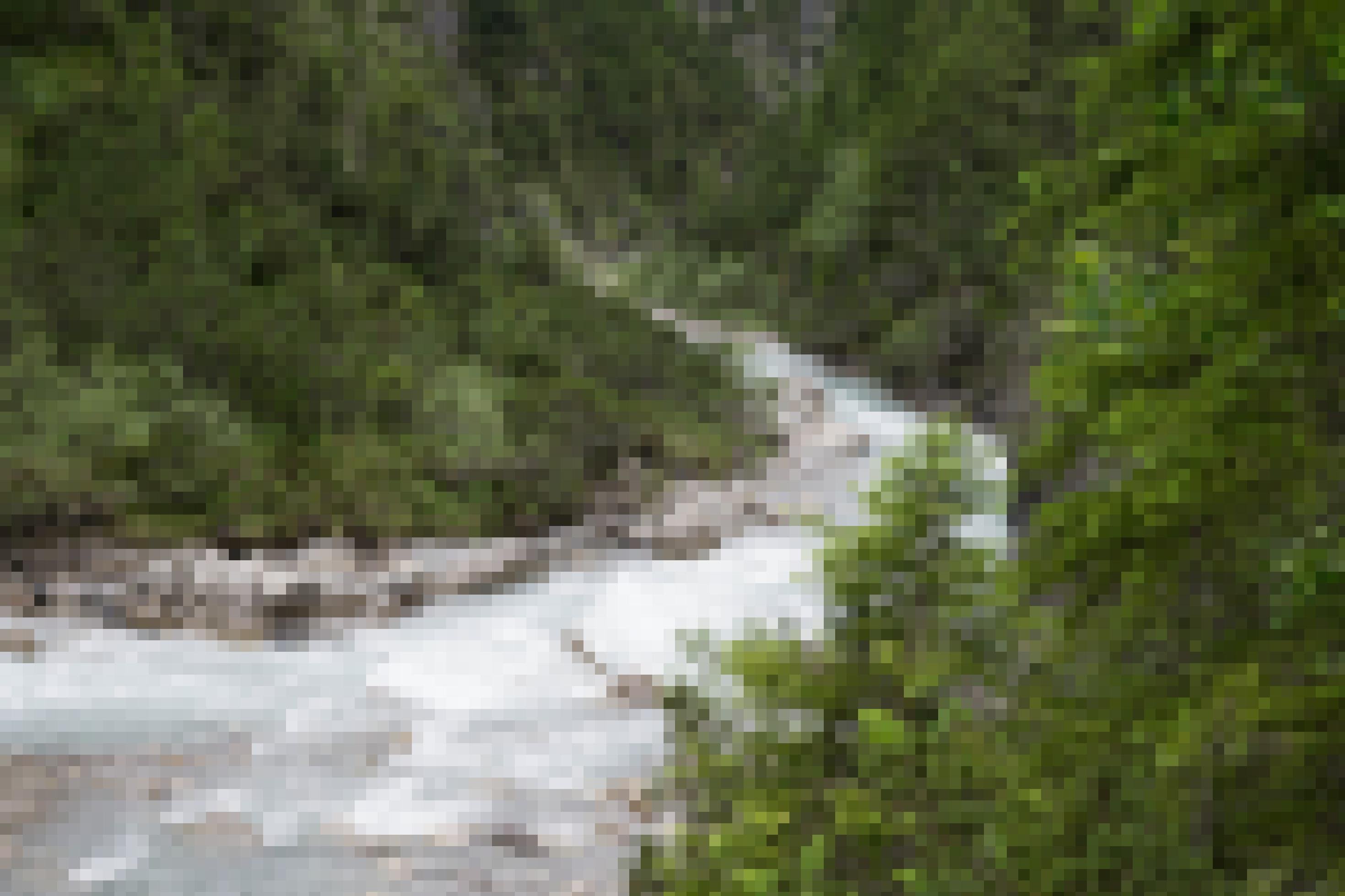 Gebirgsbach mit steiler Schlucht, Felsen und Wald.