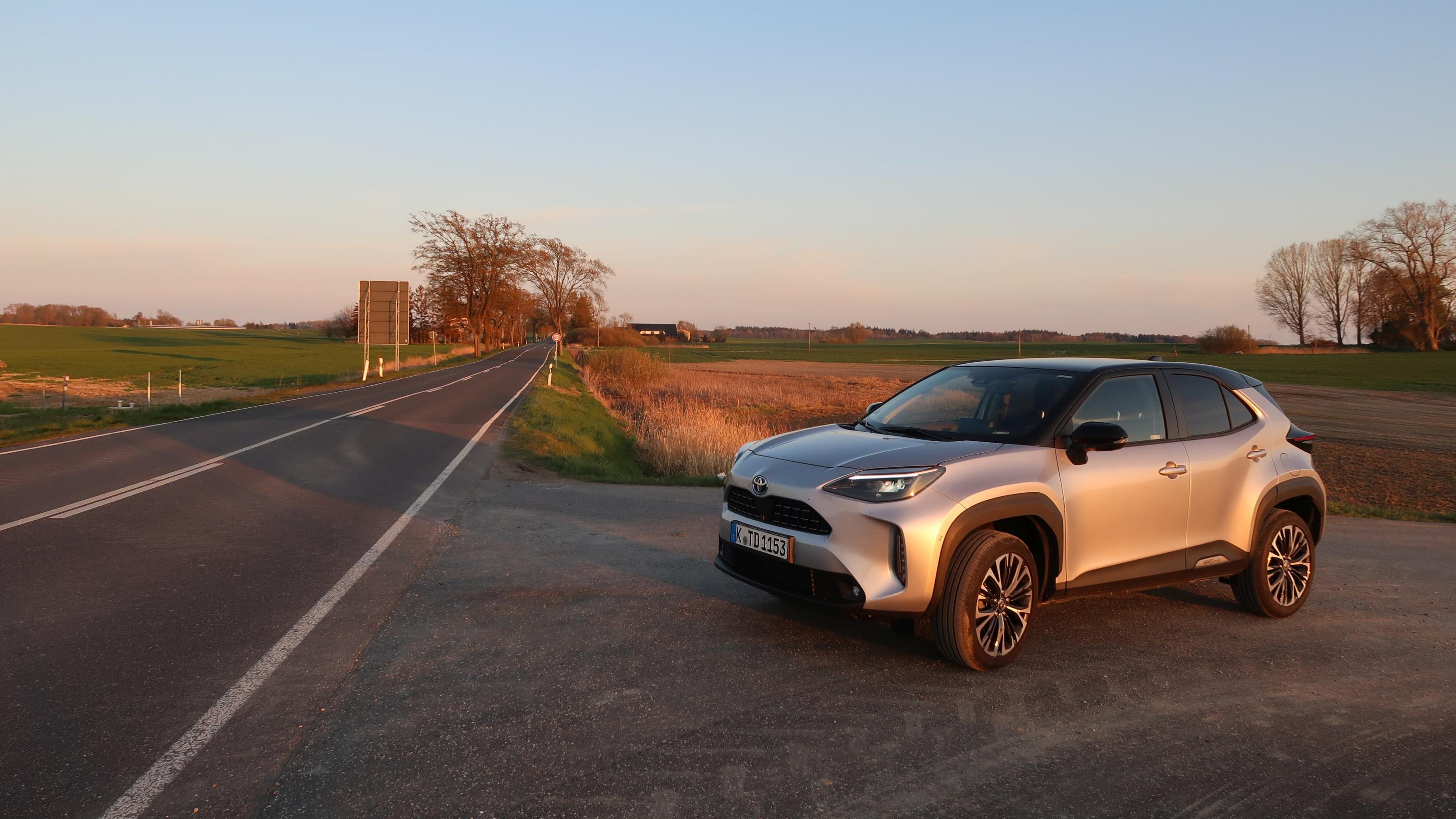 Toyota Yaris Cross parkt neben Landstraße im Sonnenuntergang