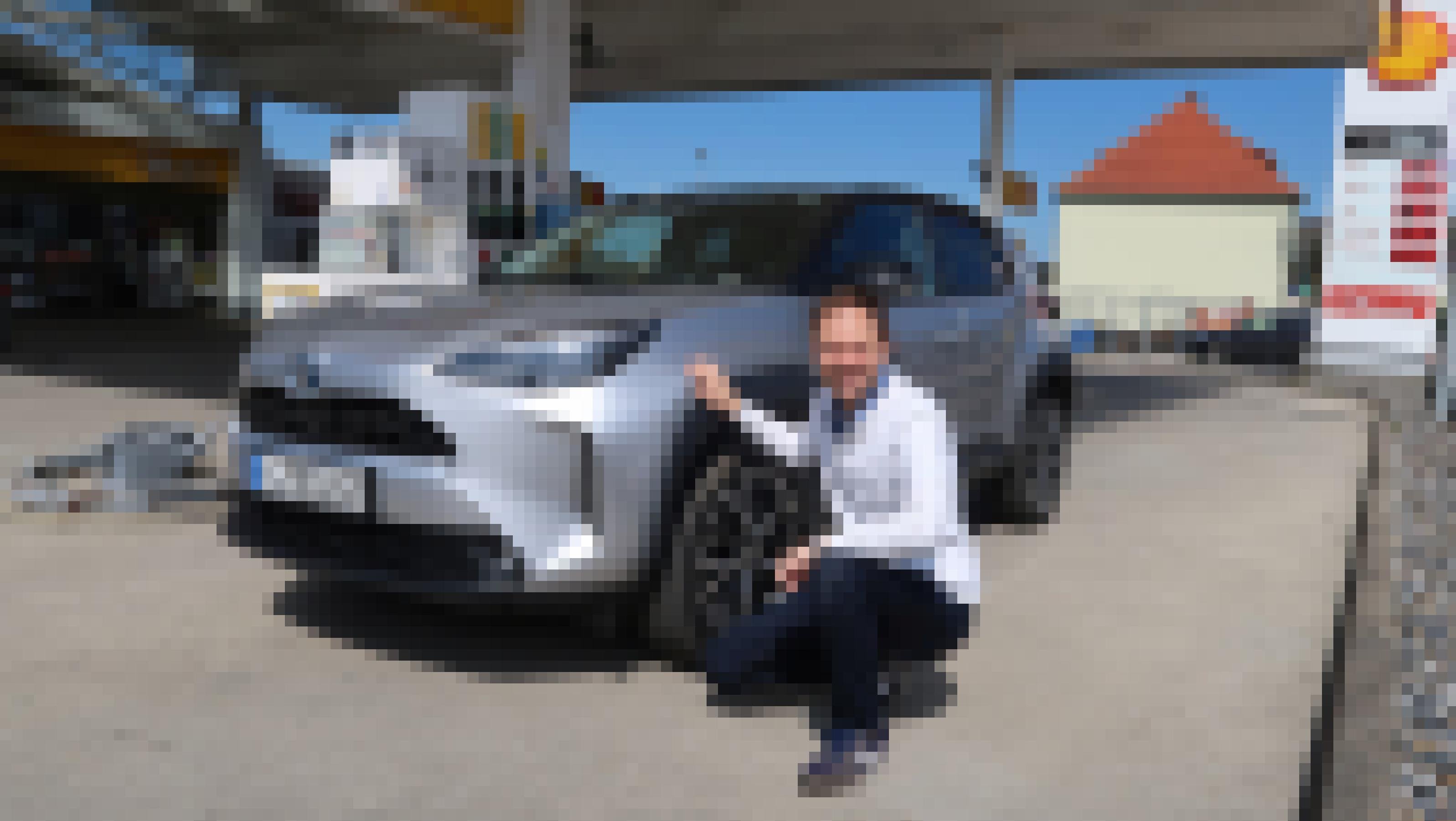 Der Autor hockt an der Tankstelle vor dem Testfahrzeug, dem Toyota Yaris Cross