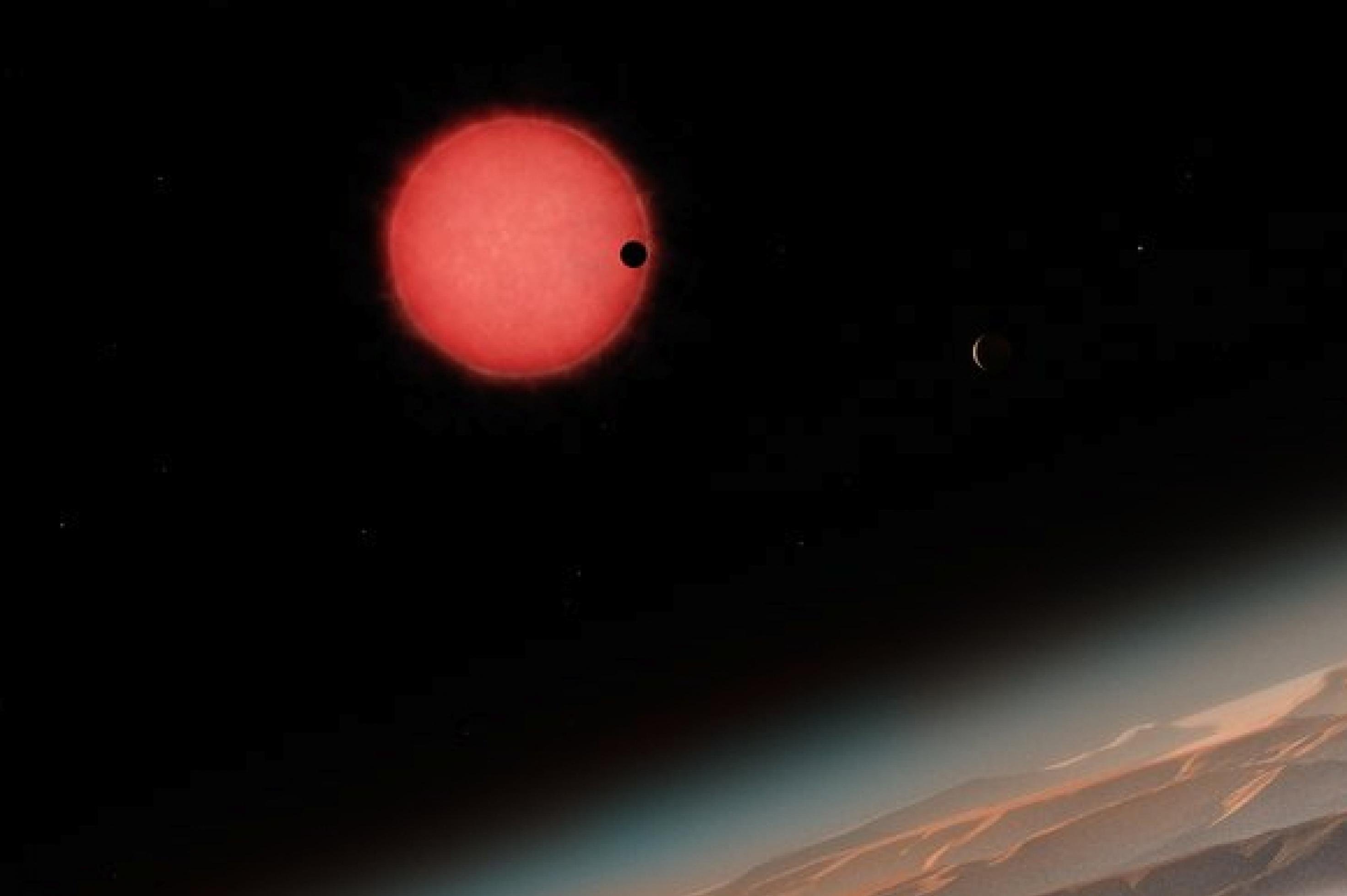 Ein Planet verdeckt einen Teil der Sonnenscheibe von TRAPPIST-1, darunter ist die Oberfläche eines der anderen Planeten angeschnitten.