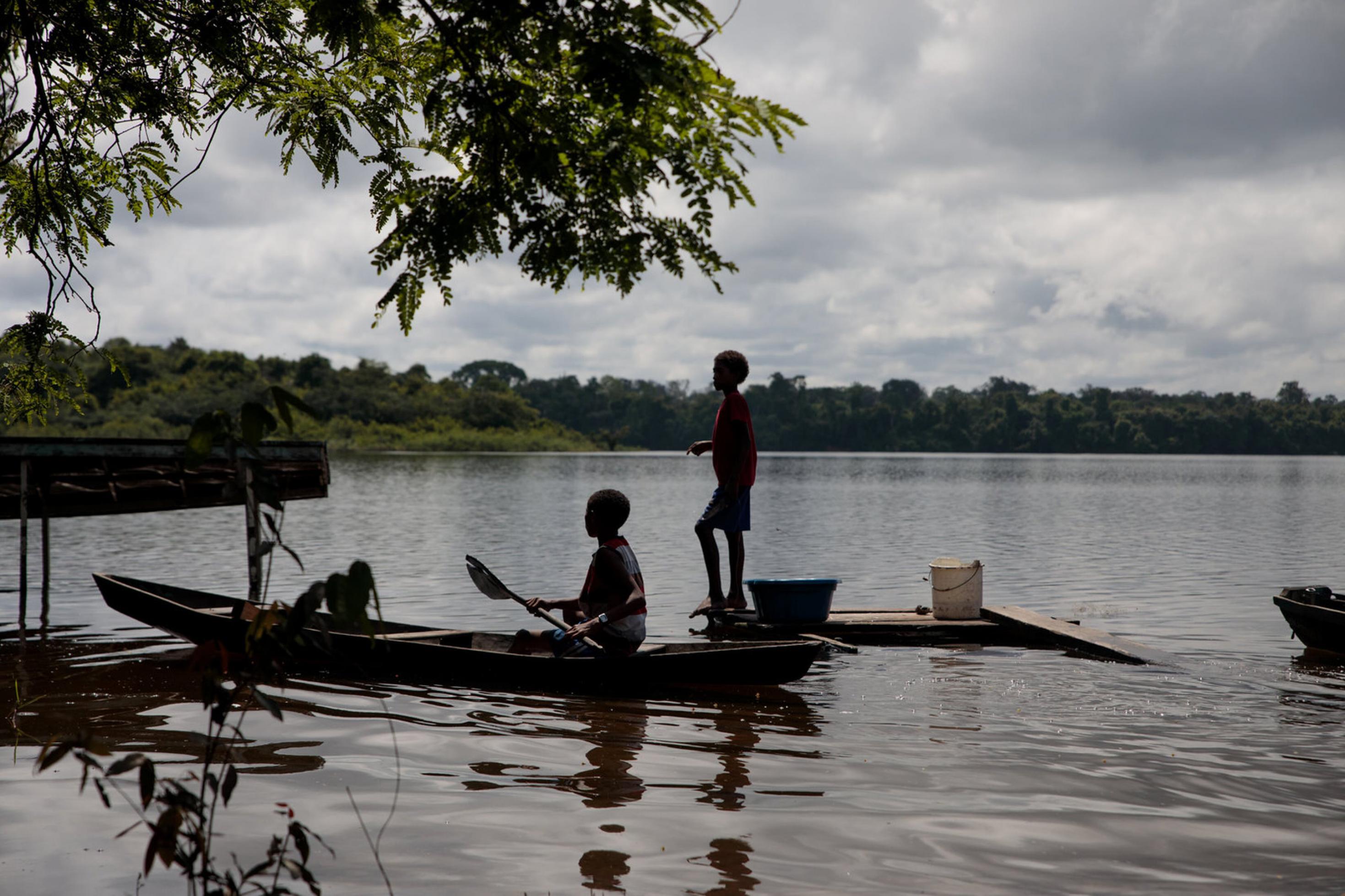 Eine Totale zeigt, wie zwei Kinder in einem schmalen Boot angeln. Sie befinden sich am Fluss Trombetas.