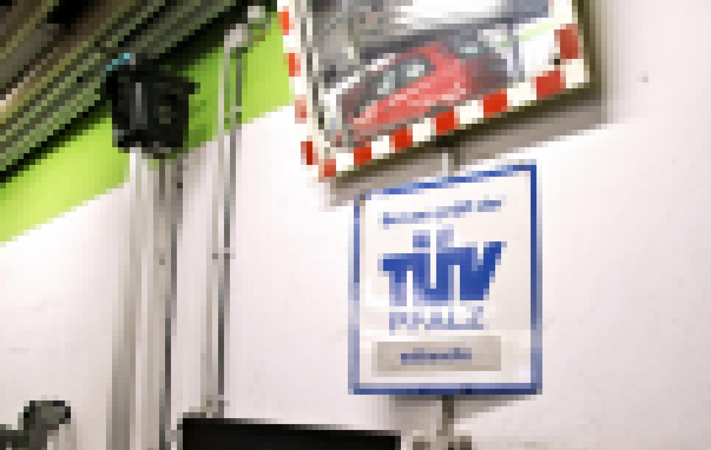 Ein Metallschild mit der Aufschrift „TÜV“ hängt an der Wand einer Werkstatt.