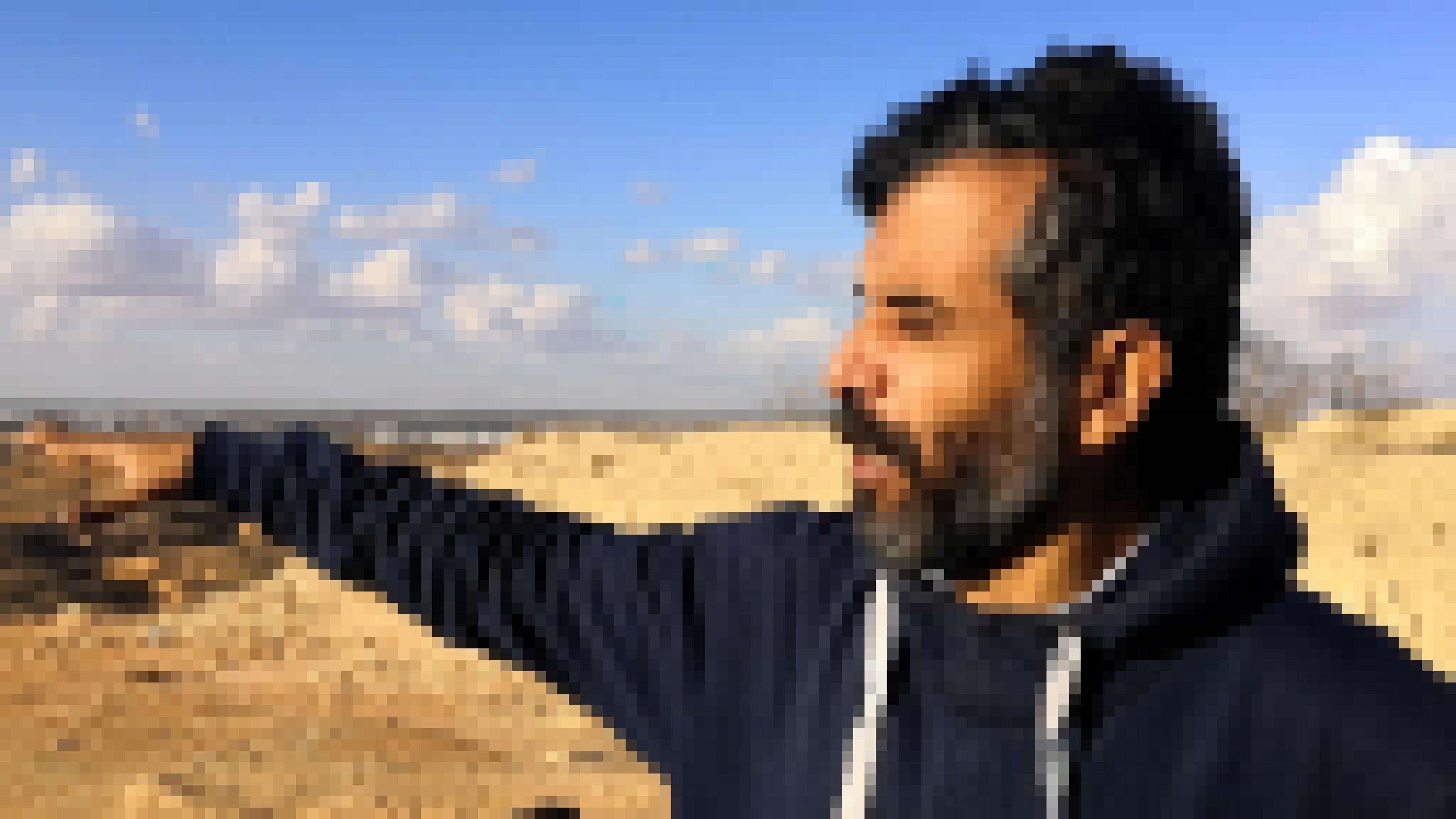 Ein Mann in Pulli mit graumeliertem Bart zeigt auf die Stadt Agareb
