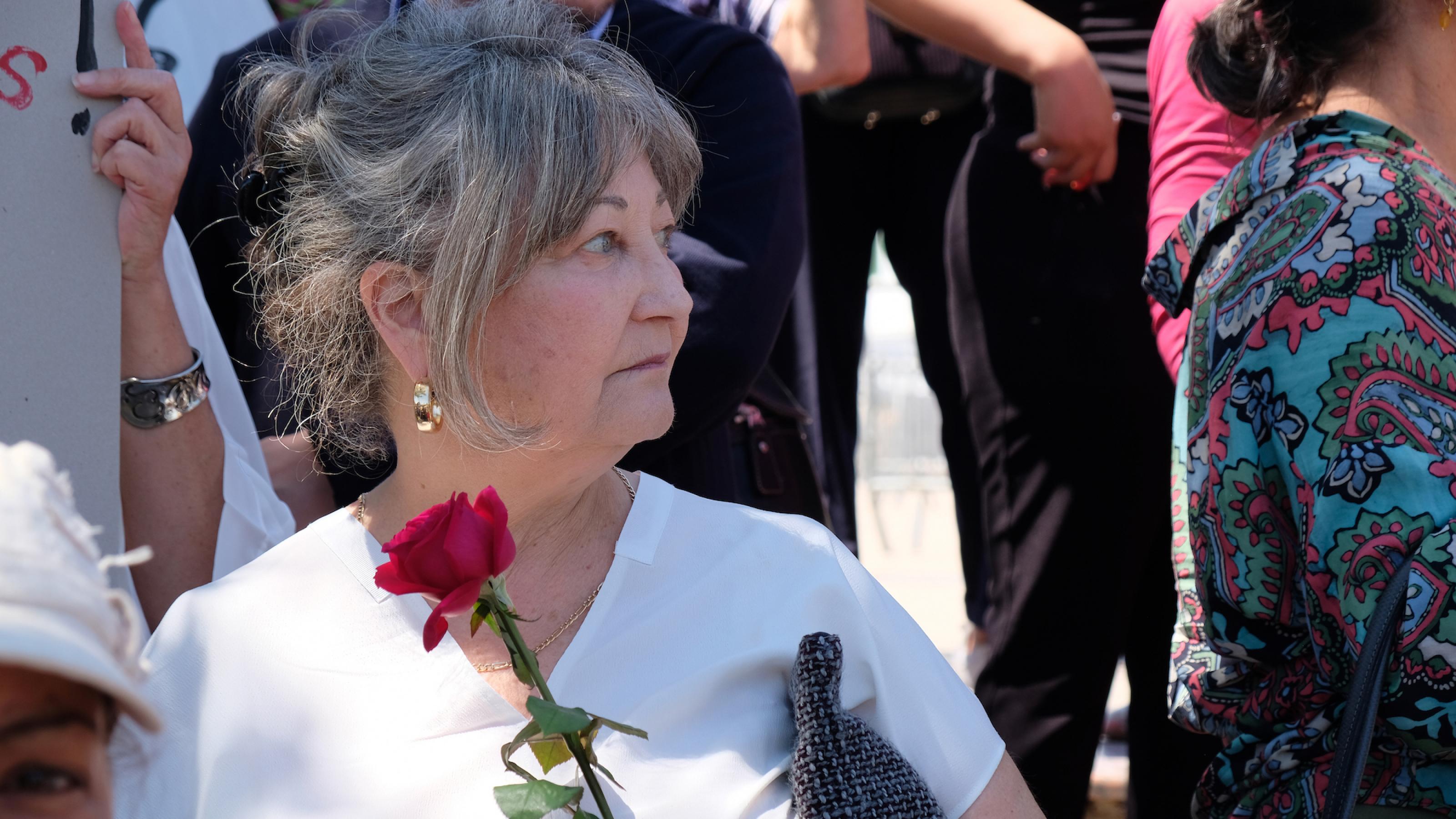 Eine Frau mit einer roten Rose in der Hand steht in Mitte von Demonstrierenden