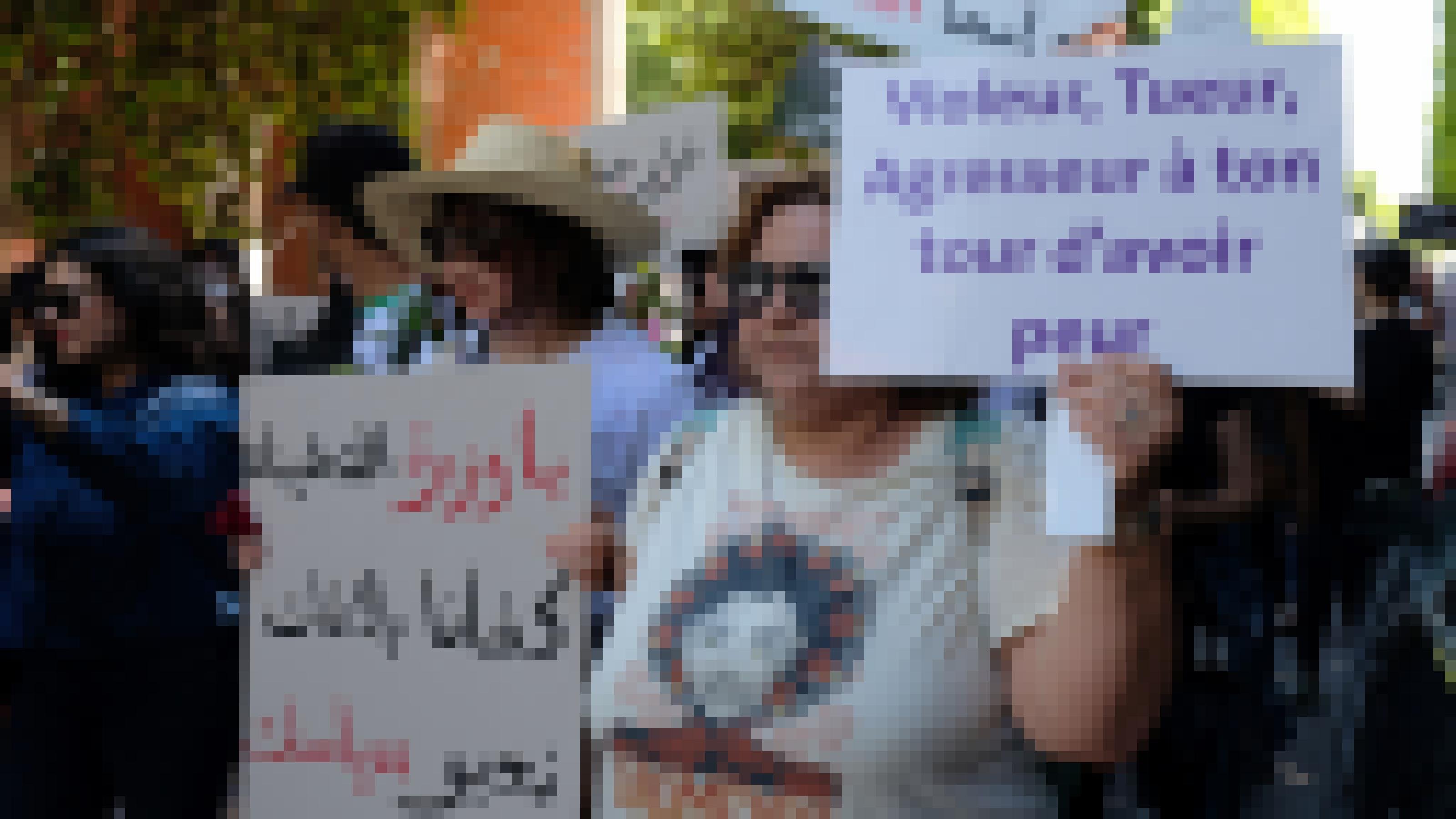 Eine Frau mit Sonnenbrille läuft in der ersten Reihe einer Demonstration. Sie trägt ein Schild, auf dem auf Französisch zu lesen ist: Vergewaltiger, Mörder, Angreifer, jetzt bist du an der Reihe, Angst zu haben"