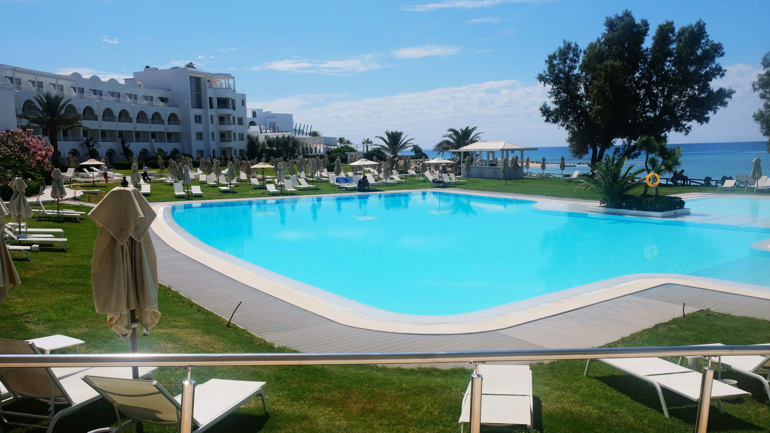Blick auf Pool und leere Liegestühle auf einer Wiese im Hotel Sultan in Hammamet, Tunesien.