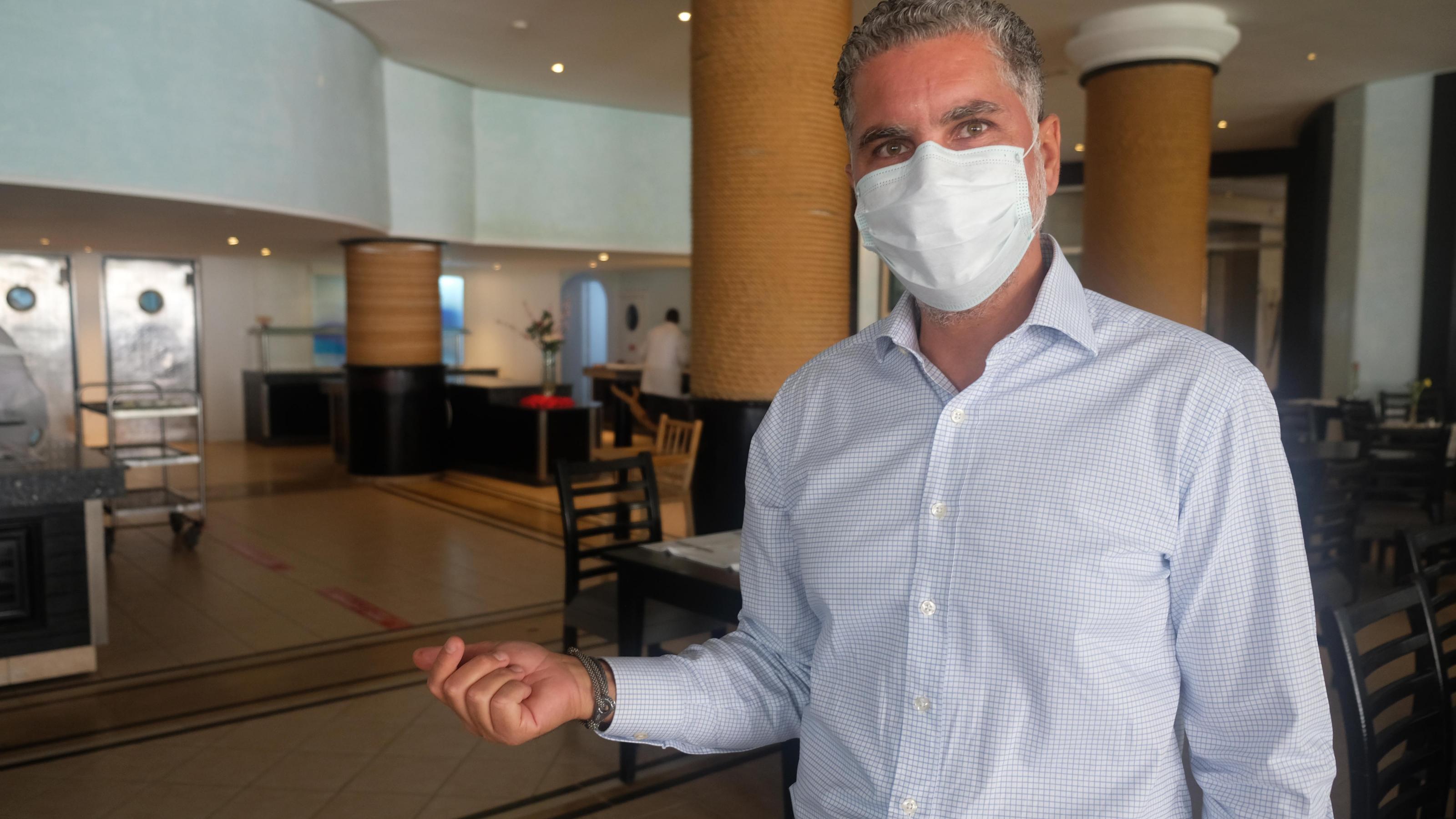 Ein Mann mit Gesichtsmaske steht im Hotelrestaurant.