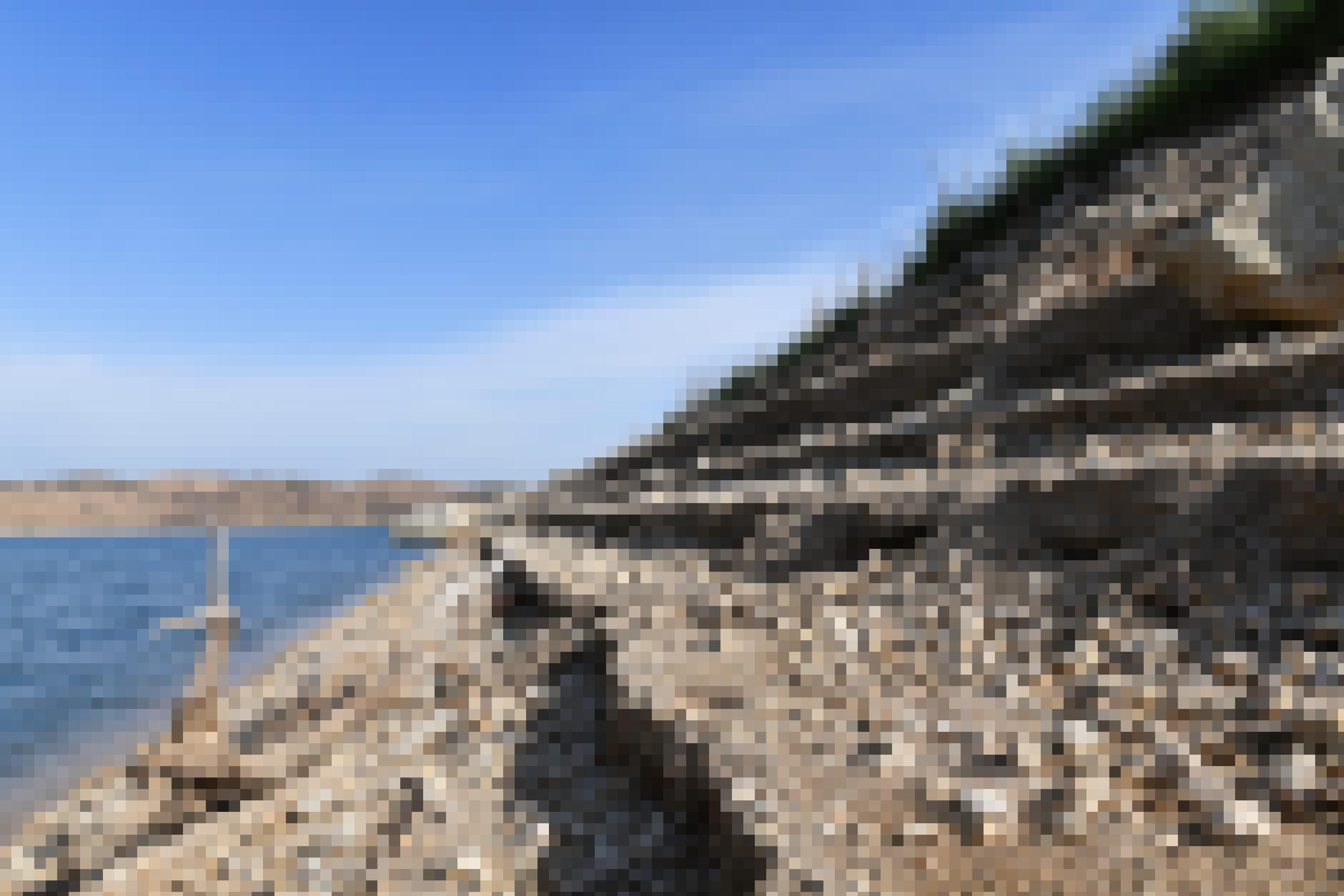 Am Rand des Staudamms sind im Geröll Stufen von vorherigen Wasserständen zu sehen.