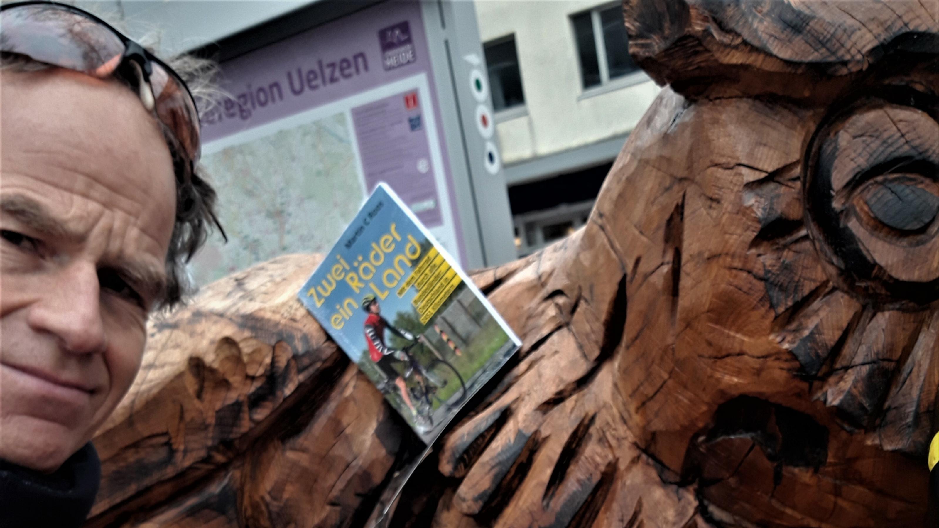 Der RadelndeReporter rastet an der riesigen Eulen-Bank mitten in Uelzen, geschaffen vom Motorsägenkünstler Andrée Löbnitz, um sein Buch „Zwei Räder, ein Land“ der Öffentlichkeit zu präsentieren.