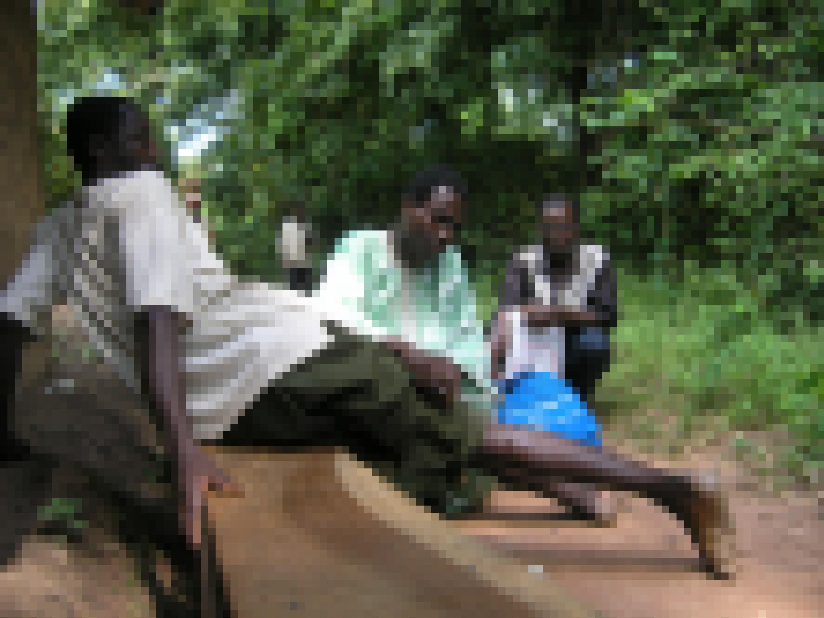 Um einen langen Guineawurm aus dem Gewebe zu entfernen, zieht ein Mann den weißen Wurm aus dem Unterschenkel eines Patienten.