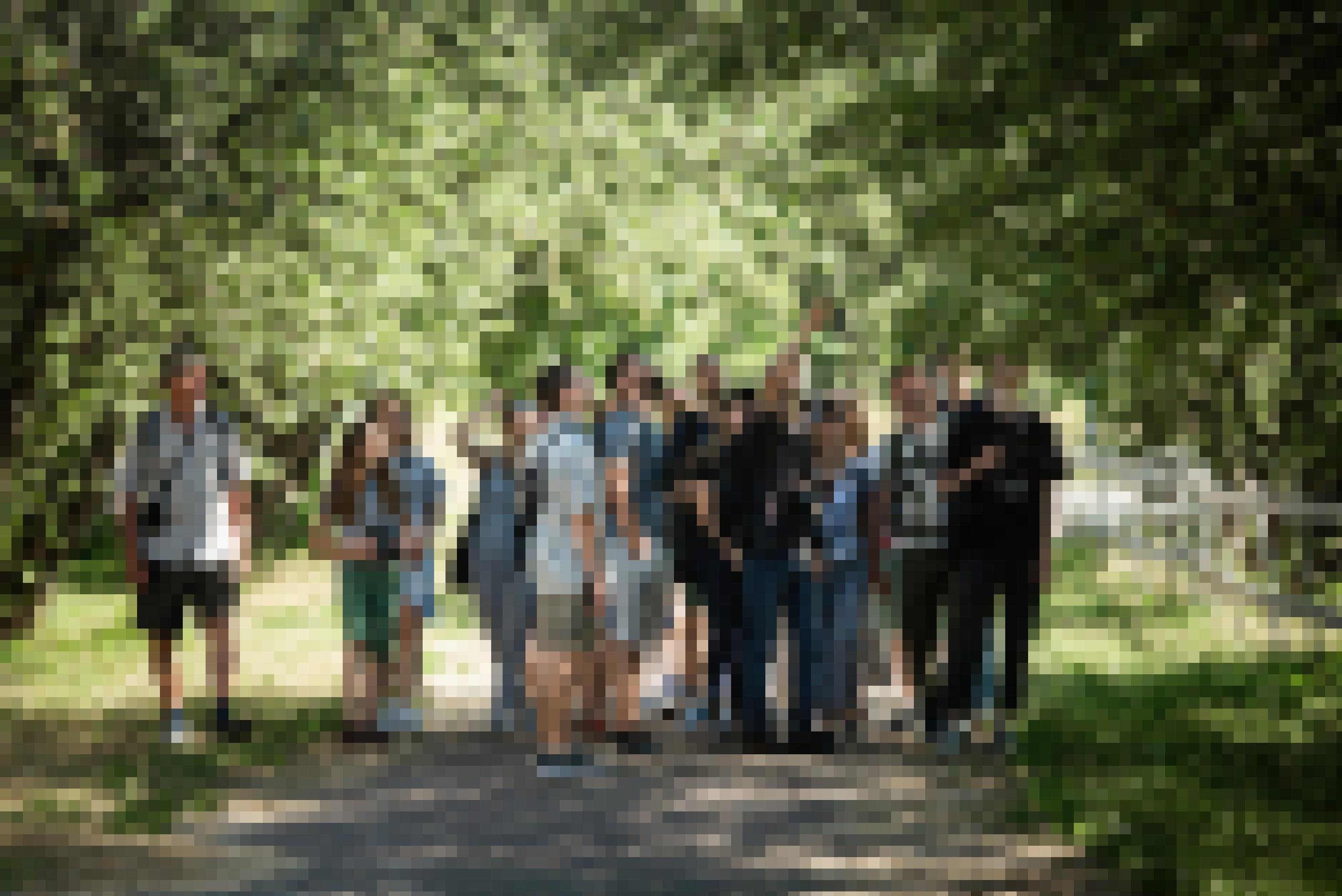 Eine Gruppe Menschen, viele mit Ferngläsern, in einem Park