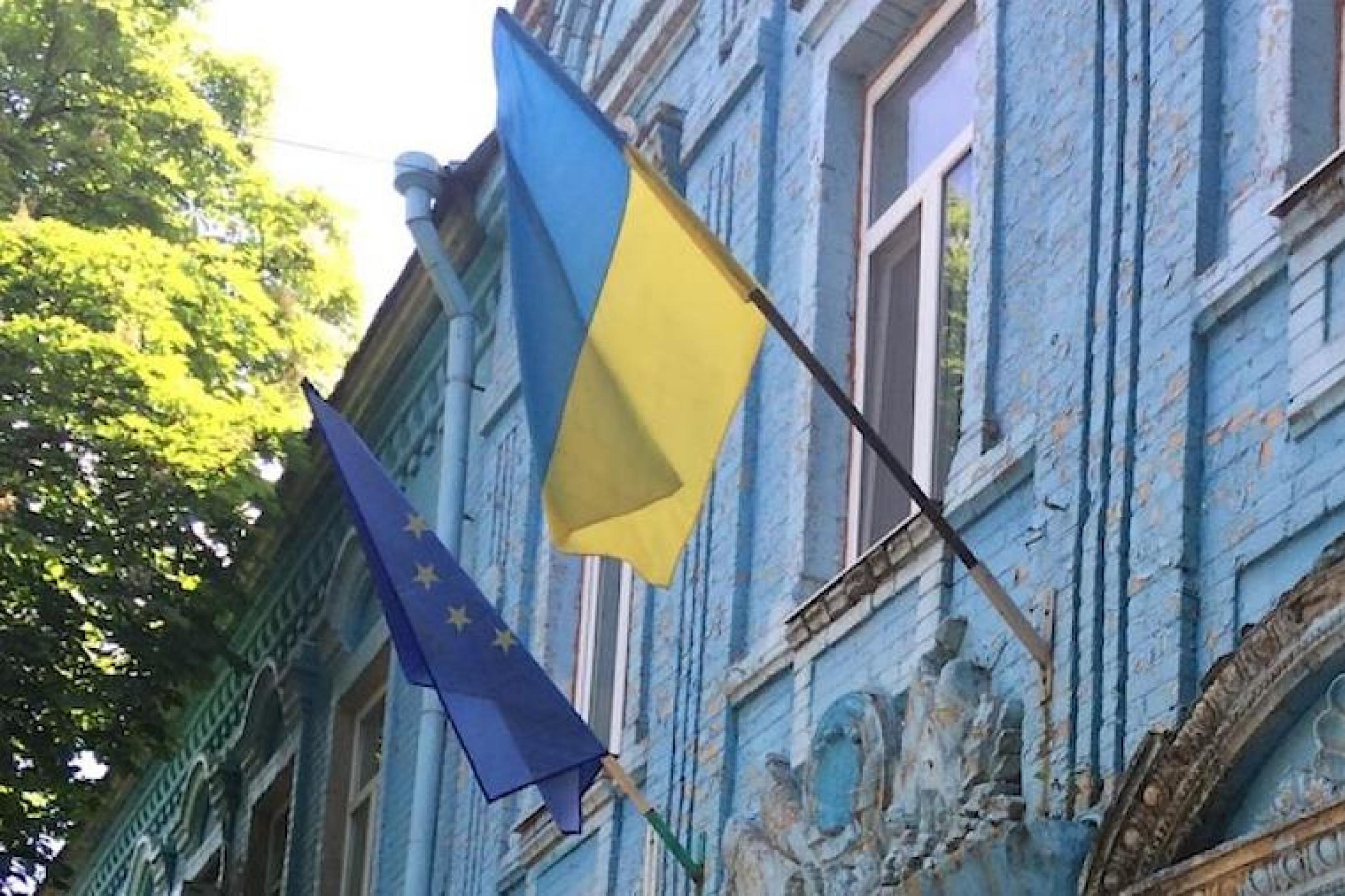 Die Flaggen der Ukraine und der EU hängen kurz vor dem Krieg am historischen Rathaus der ukrainischen Stadt Huliaipole.
