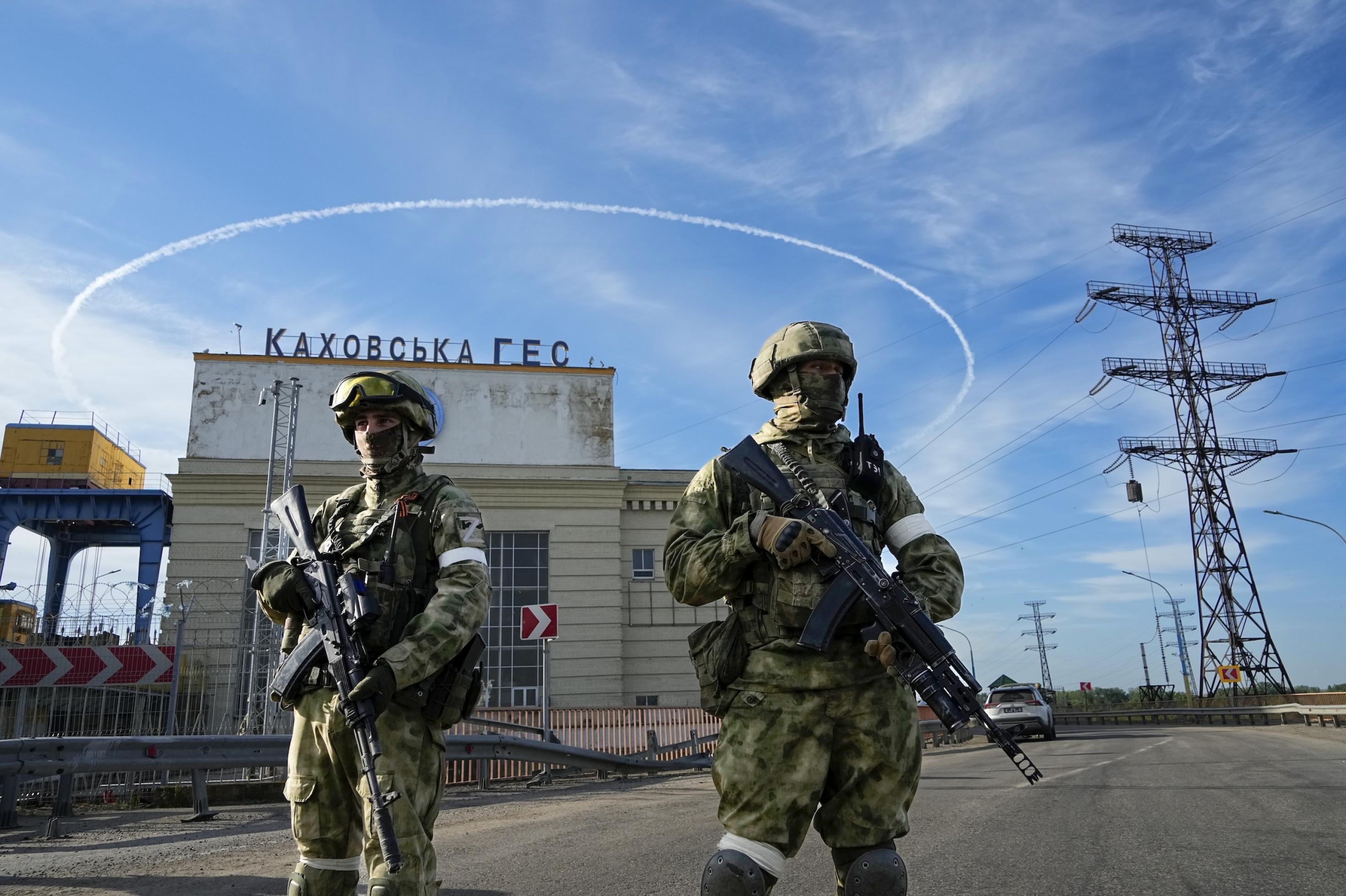 Russische Soldaten bewachen mit Gewehren in der Hand den Eingang zum Kakhovka Wasserkraftwerk am Krim-Kanal nahe Cherson.