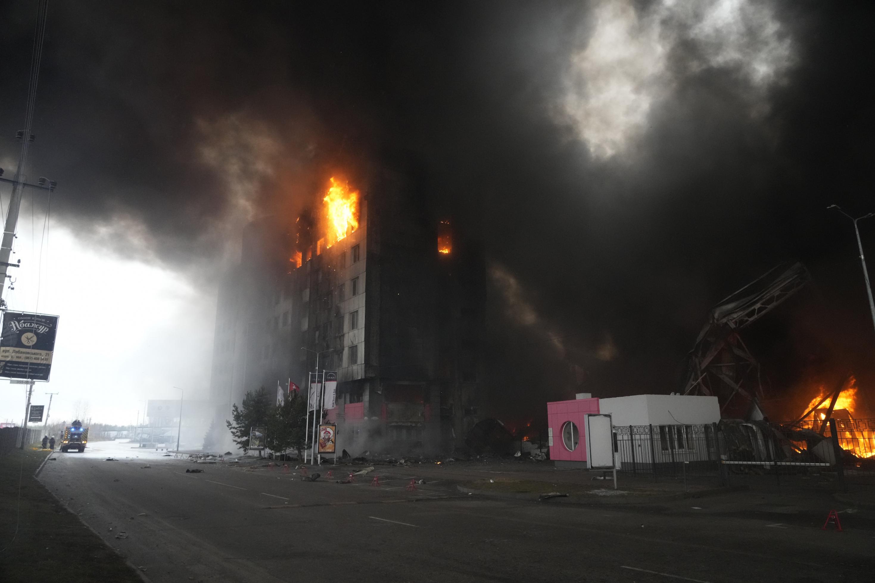 Aus einem Hochhaus dringen Flammen, dichter Rauch liegt über der Straße.