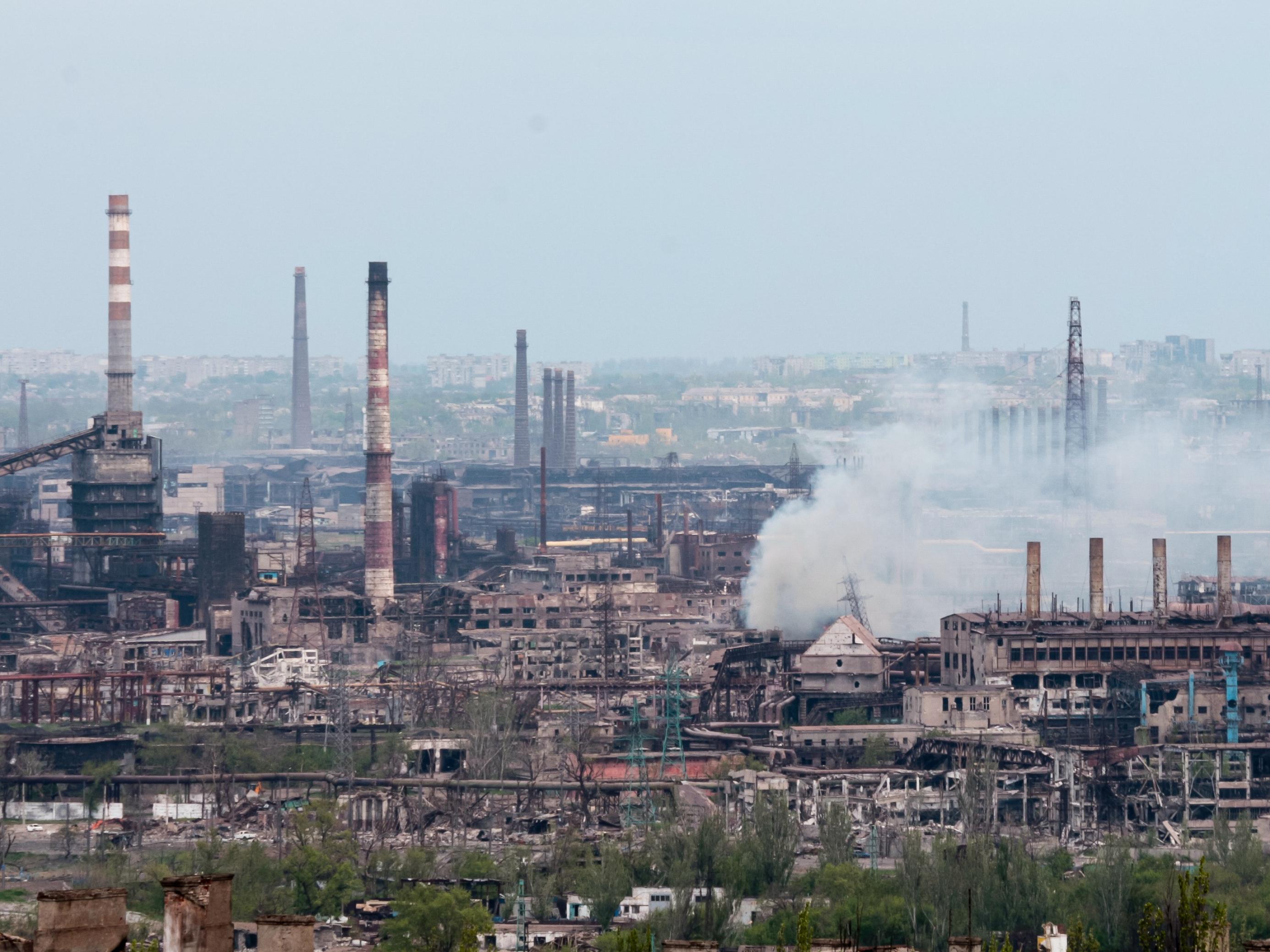 Blick auf das riesige Industriekonglomerat mit Schornsteinen und rostigen Anlagen. Rauch steigt auf.