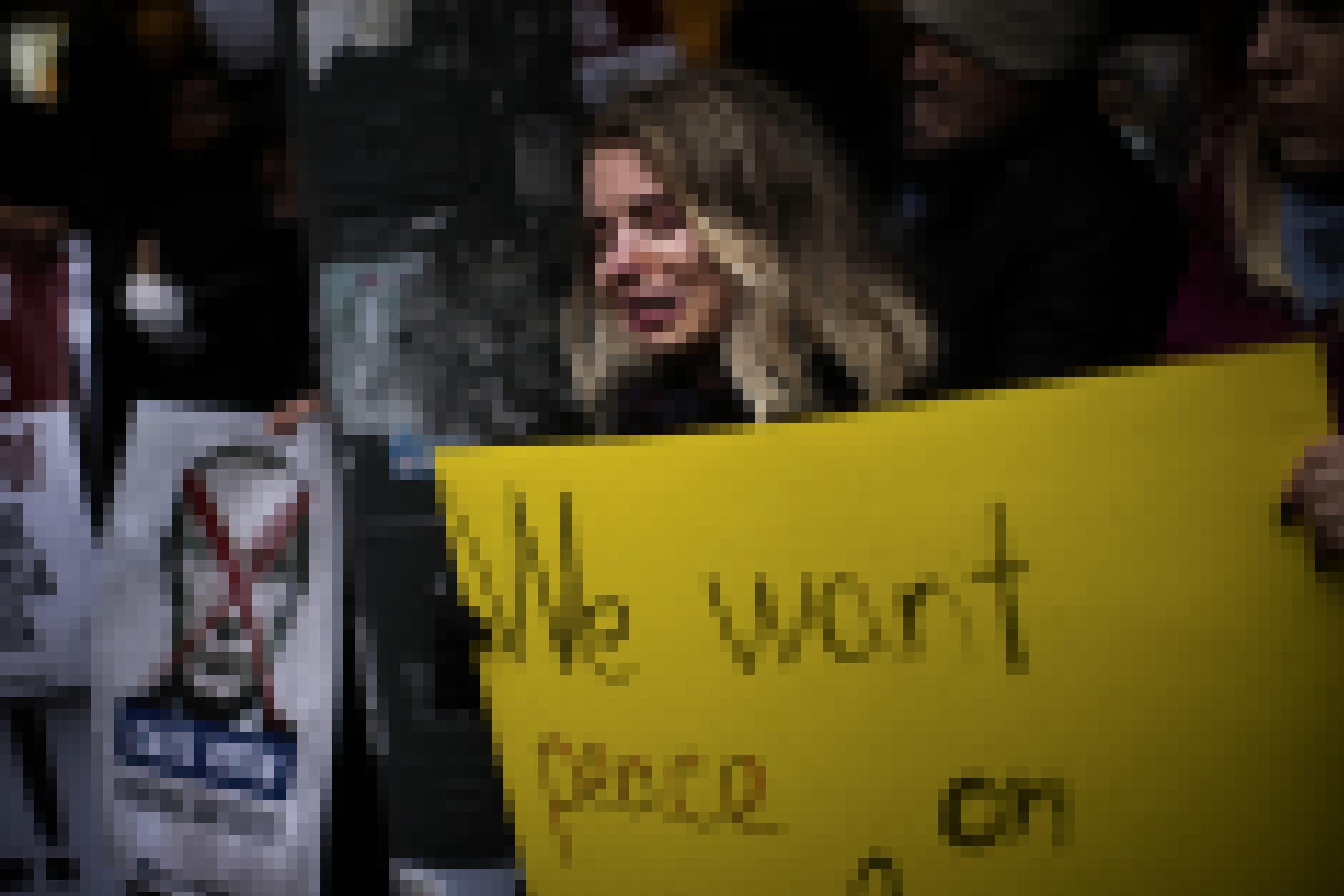 Eine Frau hält ein Plakat in die Höhe, auf dem steht: „We want peace“. Neben ihr hält ein Demonstrant ein Plakat in Türkisch hoch, das „Putin killer“ bedeutet.