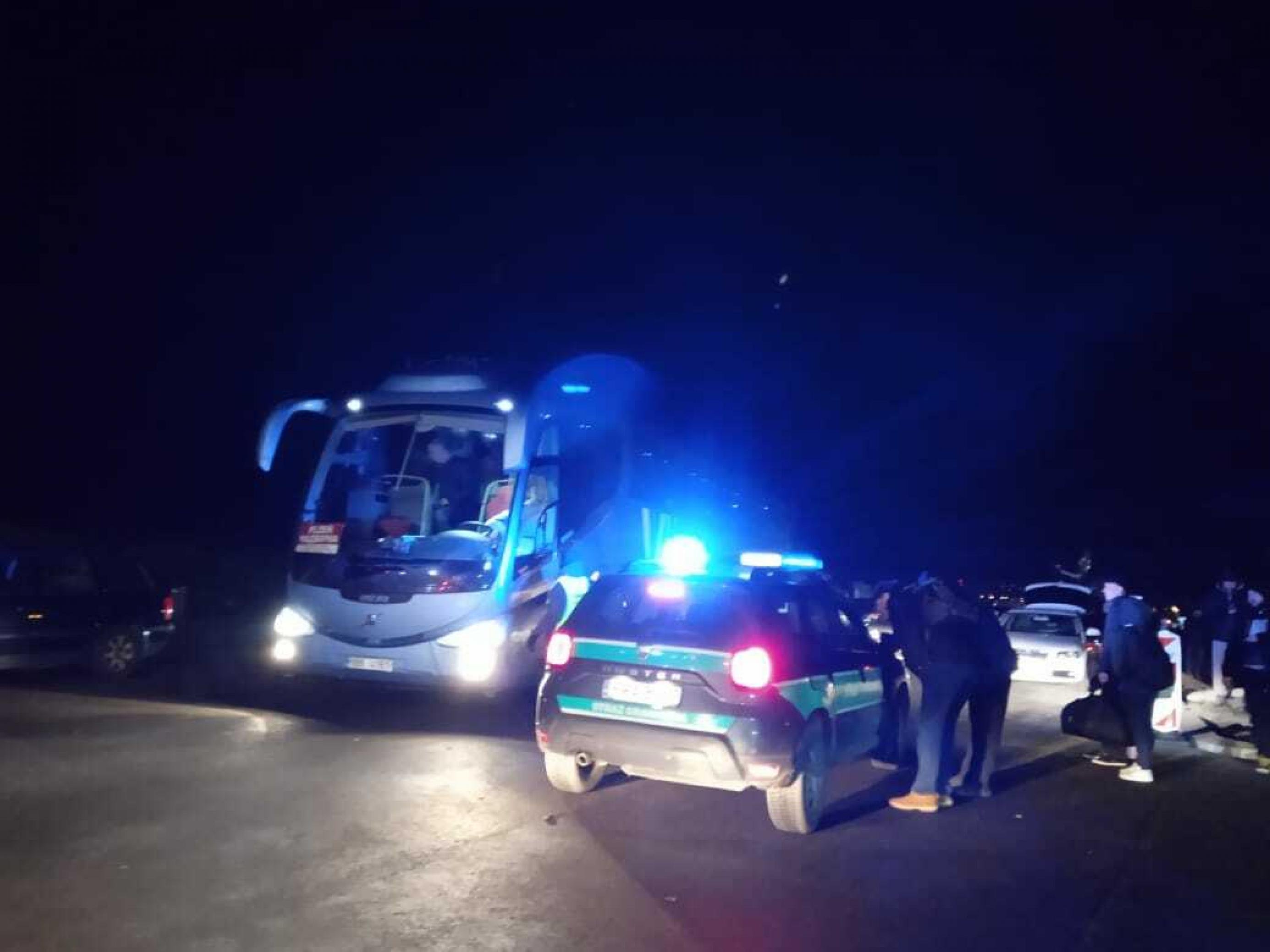 In der Nacht parkt steht ein Zollauto mit Blaulicht neben einem Reisebus mit Flüchtlingen