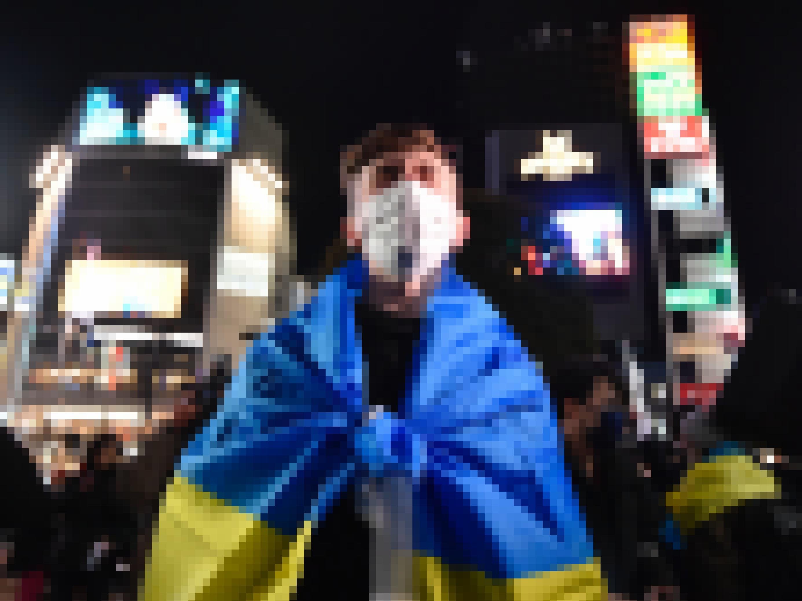 Ein junger Mann steht nachts auf einem beleuchteten Platz in Tokio. Er ist in eine Fahne in ukrainischen Farben Gelb und Blau gehüllt und hat einen verzweifelten Gesichtsausdruck.