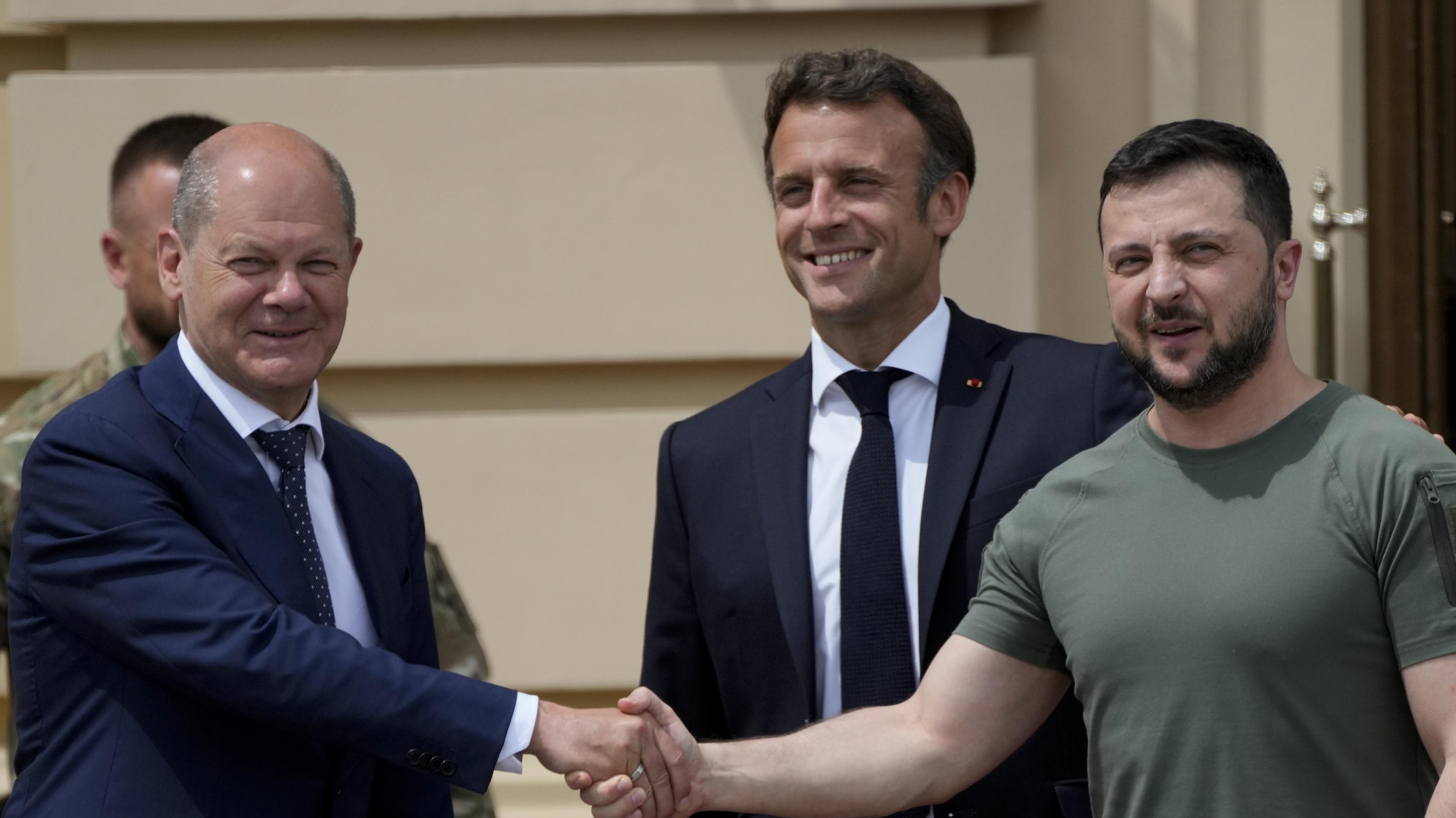 Scholz und Selenski schütteln die Hände, Macron lächelt breit