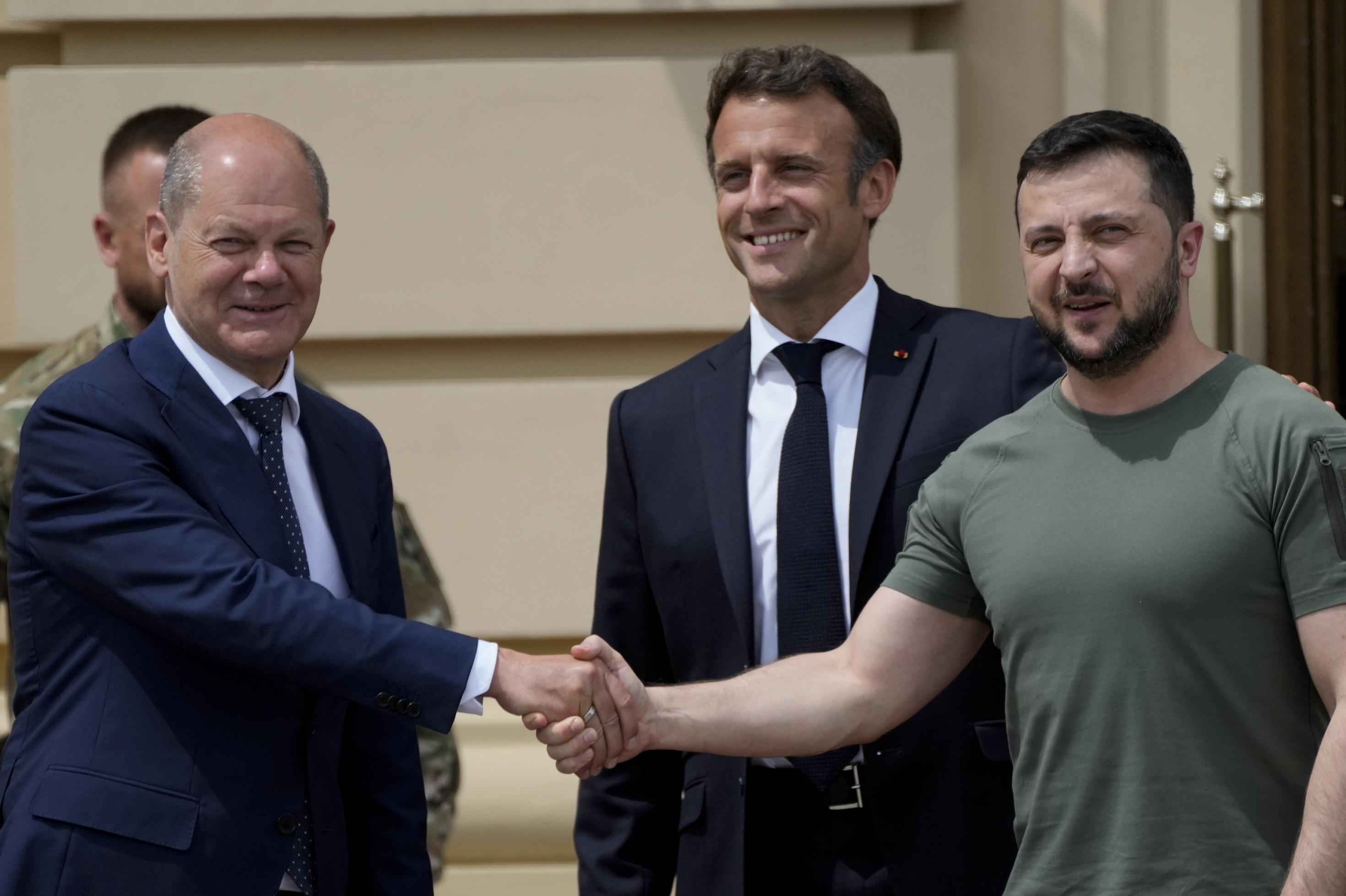 Scholz und Selenski schütteln die Hände, Macron lächelt breit