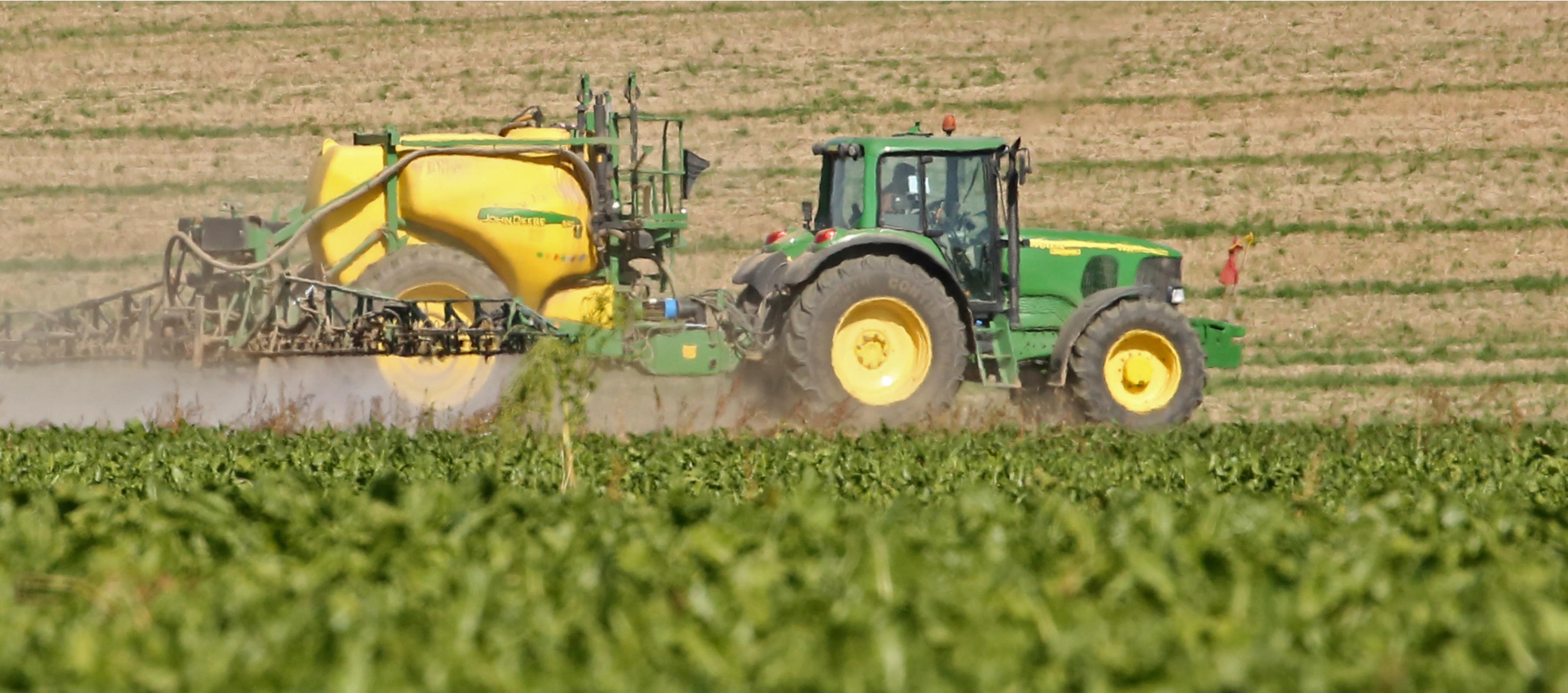 Ein Traktor mit Chemikalienanhänger auf einem Acker