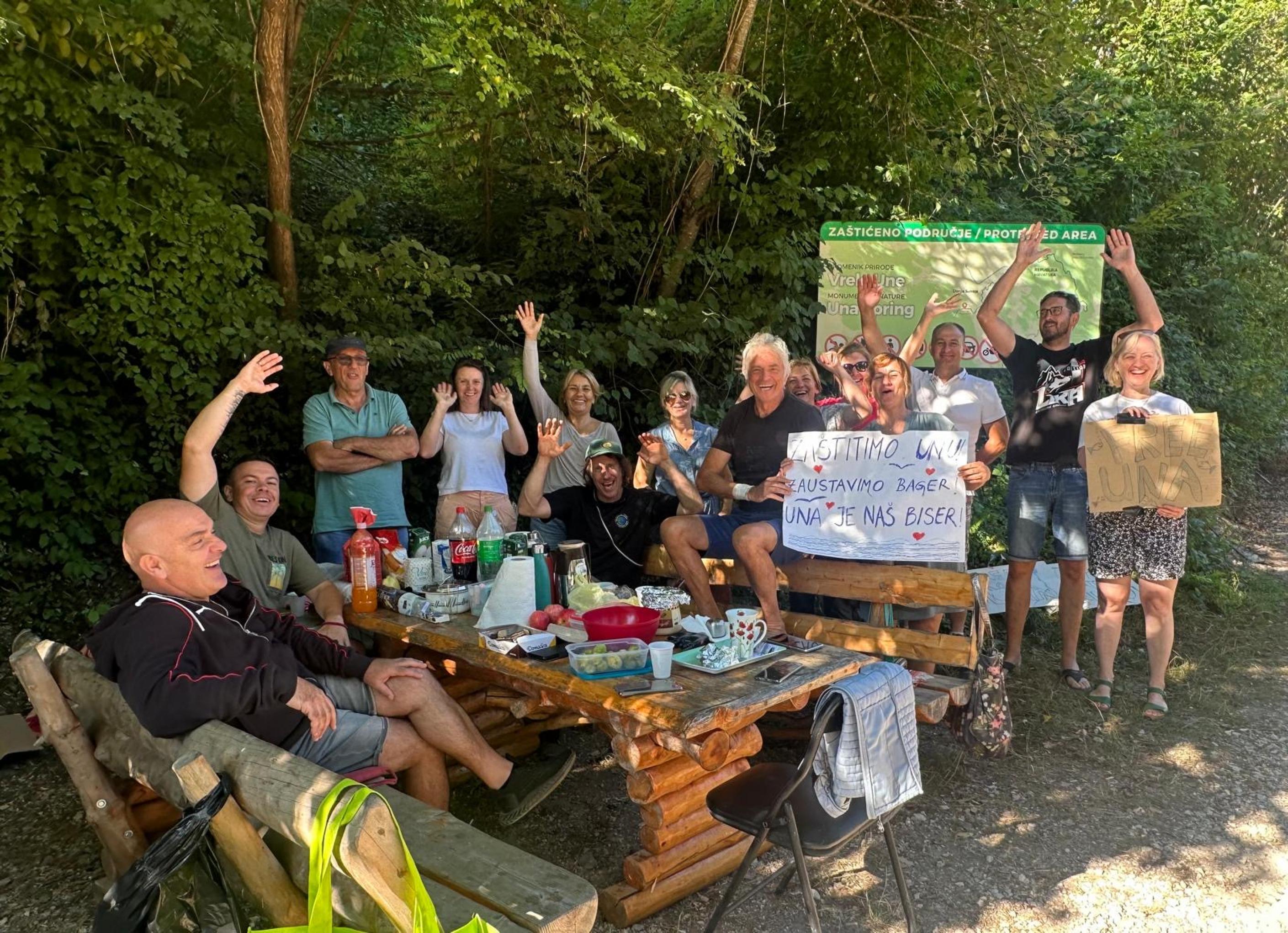 Gruppe von lachenden Menschen an Holztisch im Freien