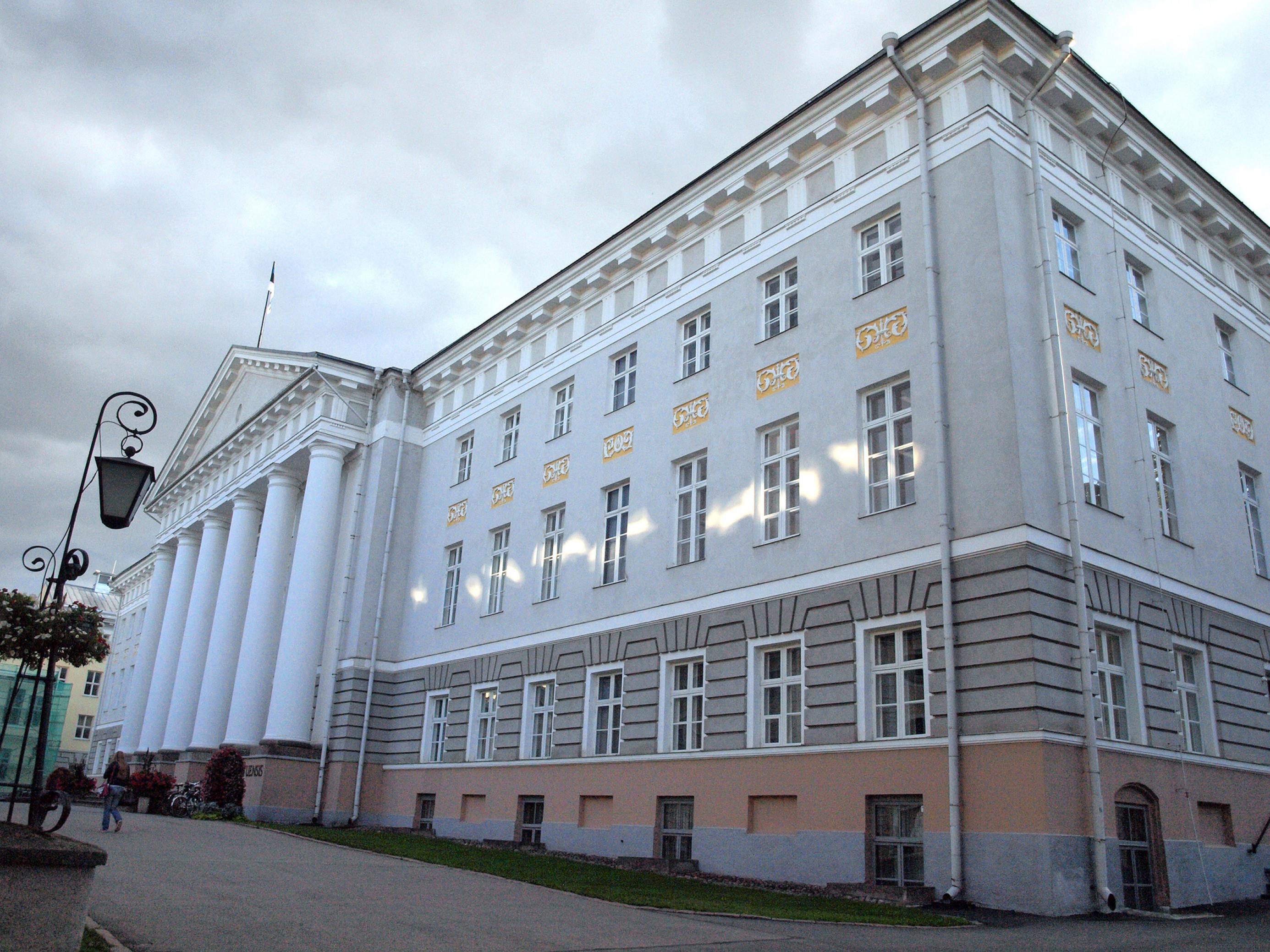 Das Foto zeigt das Hauptgebäude der Universität von Tartu in Estland. Es ist in klassizistischem Stil errichtet und leuchtet in weiß-grauen Farbtönen vor einem grau bedeckten Himmel. An dieser Universität forscht der Genetiker Michael Dannemann. Er ermittelte am Erbmaterial von mehr als 200.000 Japanern, dass deren Neandertaler-Erbe unter anderem die Wahrscheinlichkeit vermindert, an Prostata-Krebs zu erkranken.