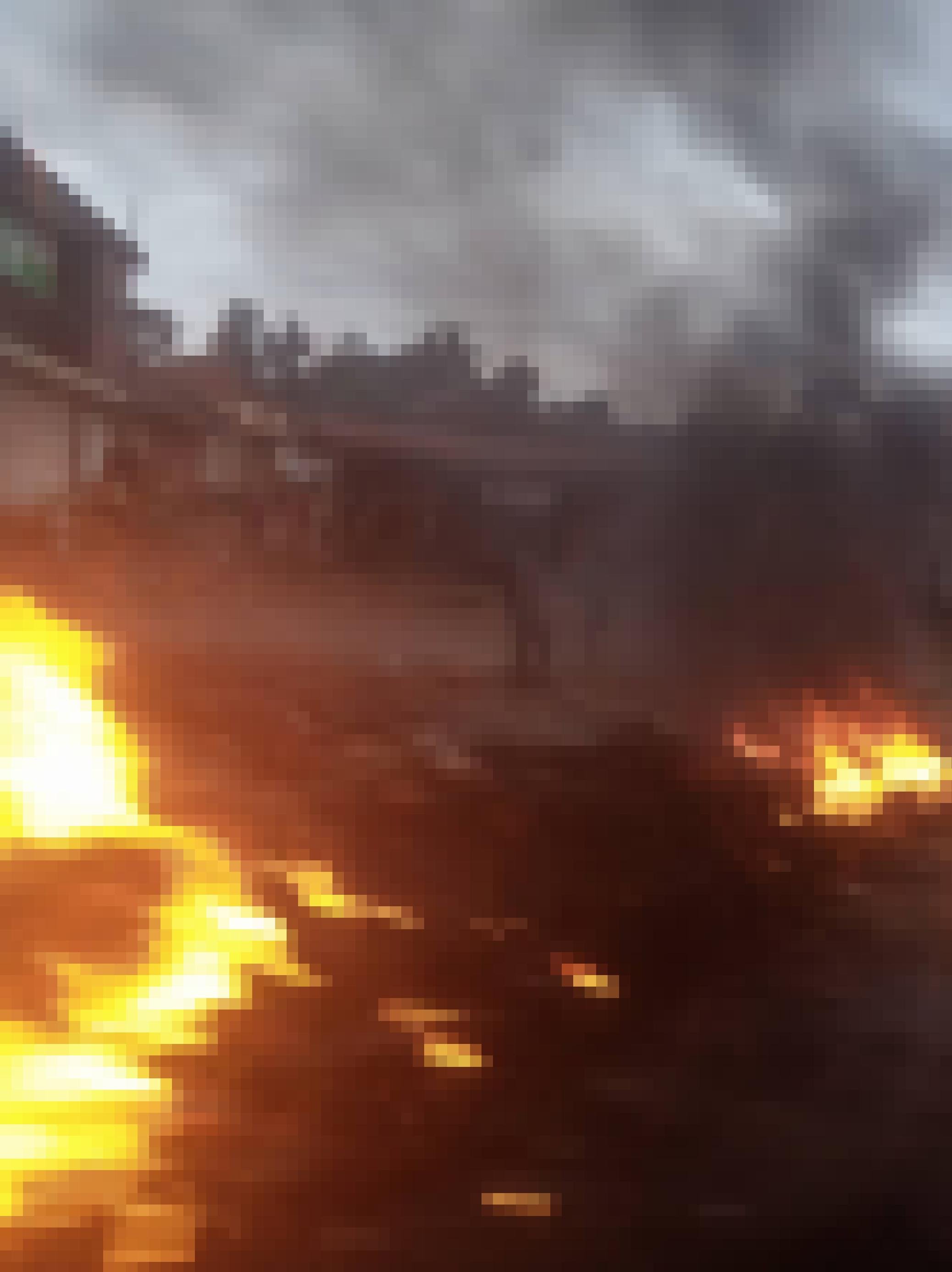 Zu sehen ist eine Straßenblockade aus brennenden Autoreifen, Rauch hängt in der Luft. Das Foto ist unscharf, was den Eindruck von Aktion, Bewegung und Gefahr unterstreicht.