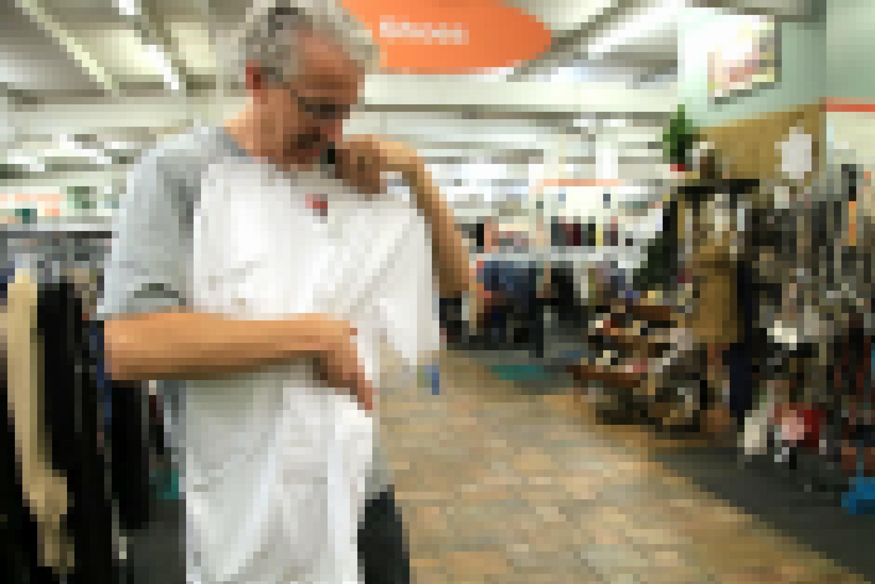 Ein grauhaariger Mann betrachtet ein Unterhemd in einem Supermarkt.