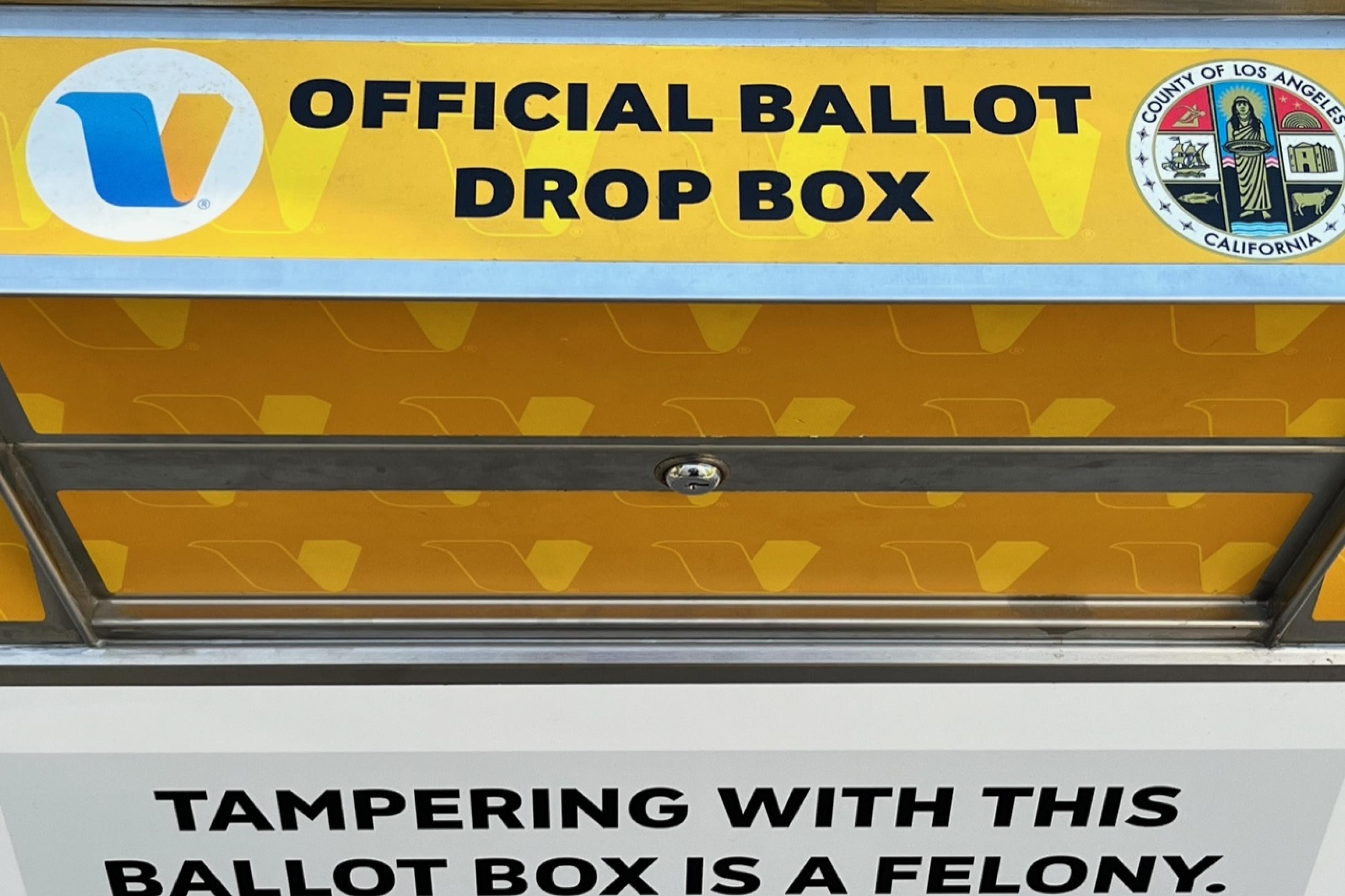 Ein gelber Container mit der Aufschrift 'Official Ballot Drop Box' und dem Wappen des Bezirks von Los Angeles. Hier können Wählerinnen und Wähler ihre Stimmzettel schon Wochen vor dem Wahltermin einwerfen.