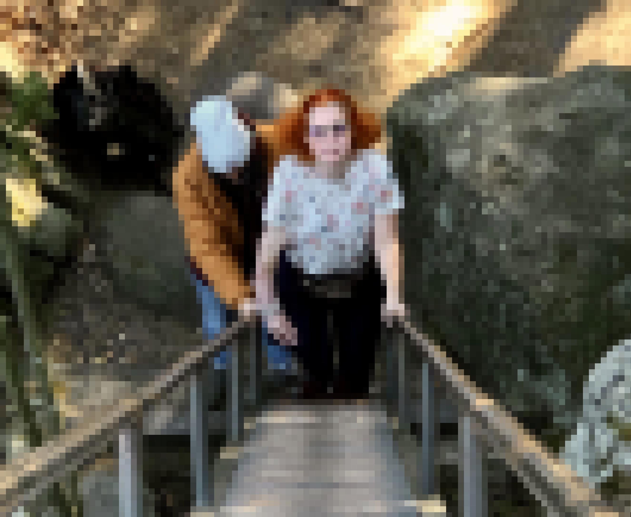 Eine Frau steht am Fuß einer Treppe im Wald. Ein Mann steht direkt hinter ihr