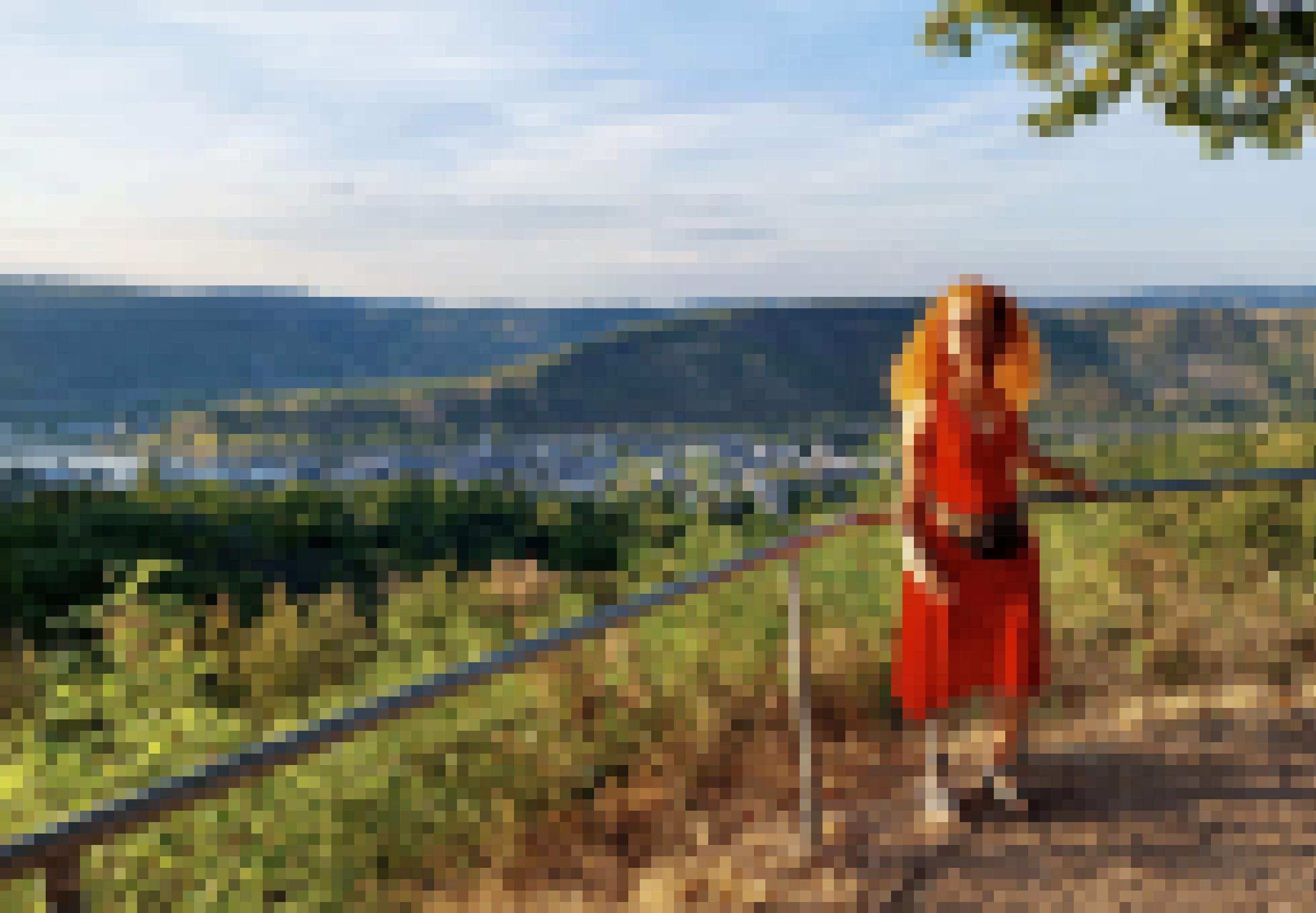 Eine Frau steht an einem Geländer. Im Hintergrund befinden sich ein Fluss und Hügel