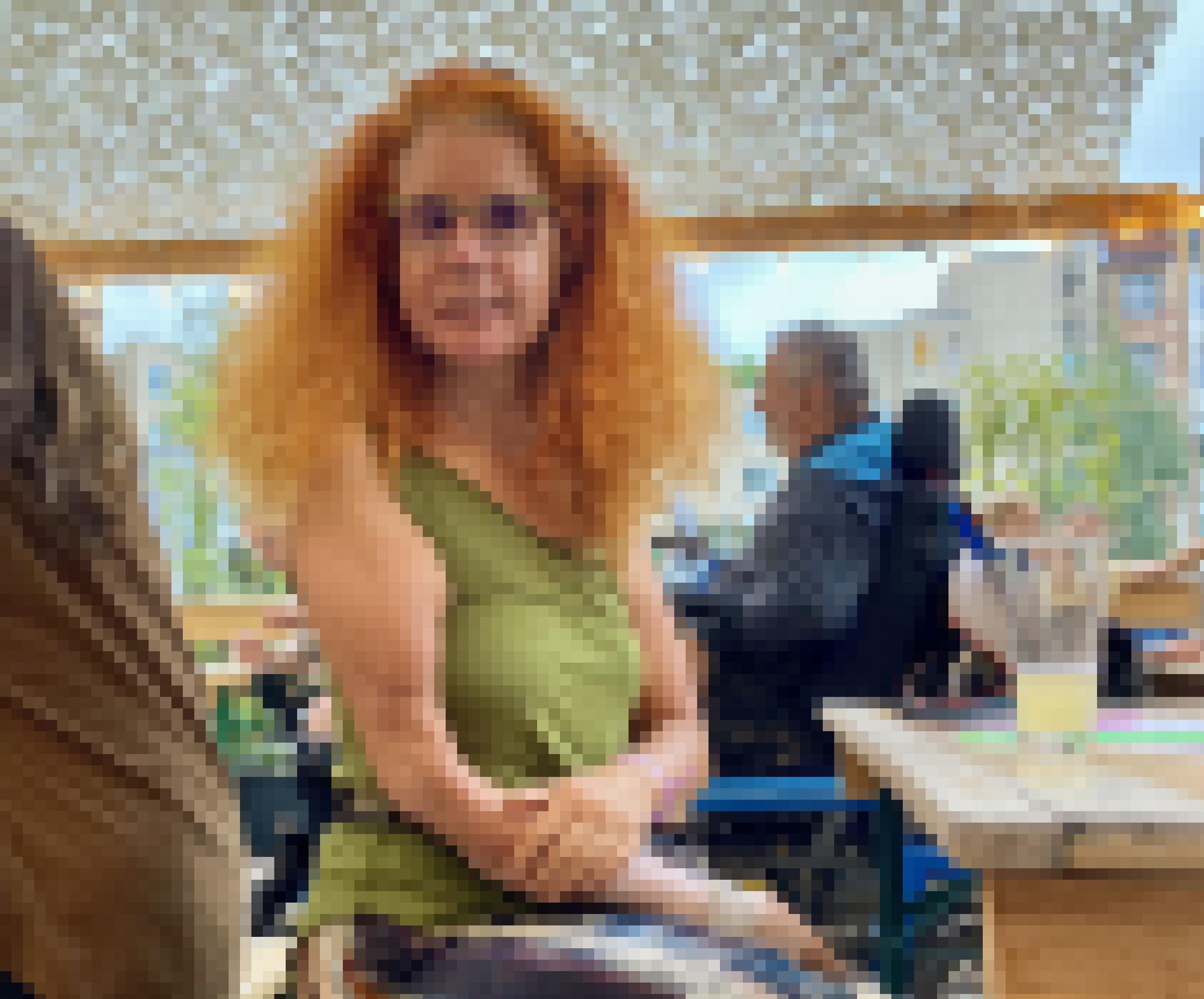 Eine Frau sitzt auf einer Bierbank vor einem Cafe