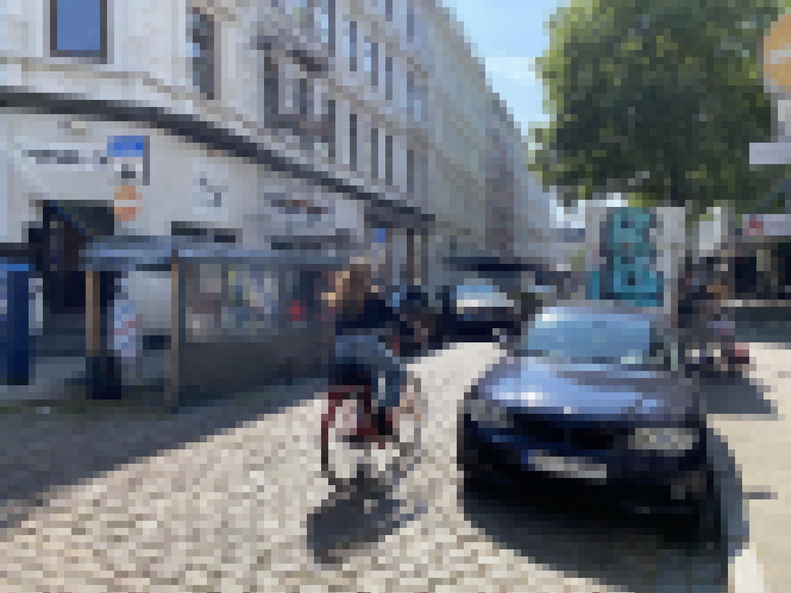 In der Straße parken am rechten und linken Fahrbahnrand Autos. Eine Radfahrerin radelt über das Kopfsteinpflaster