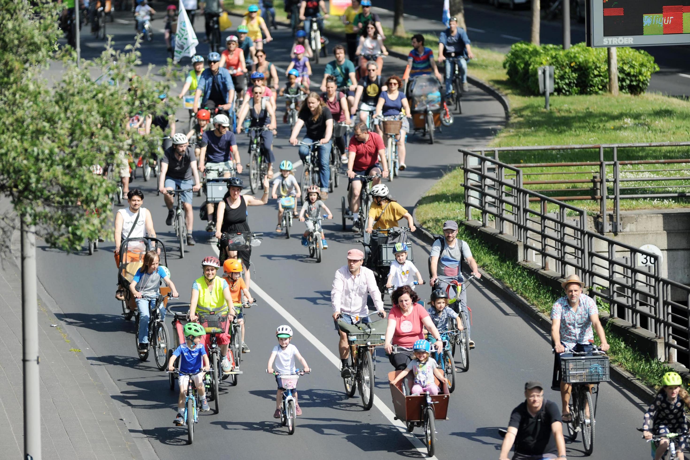 Erwachsene und Kinder radeln eine Straße entlang