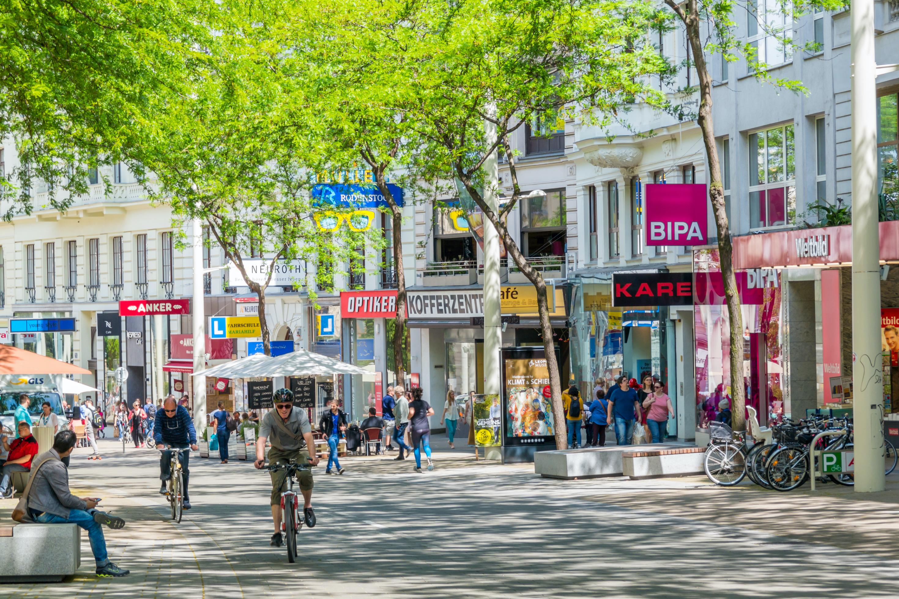 Radfahrer und Passanten sind in der Einkaufsstraße, Mariahilfer, in Wien unterwegs
