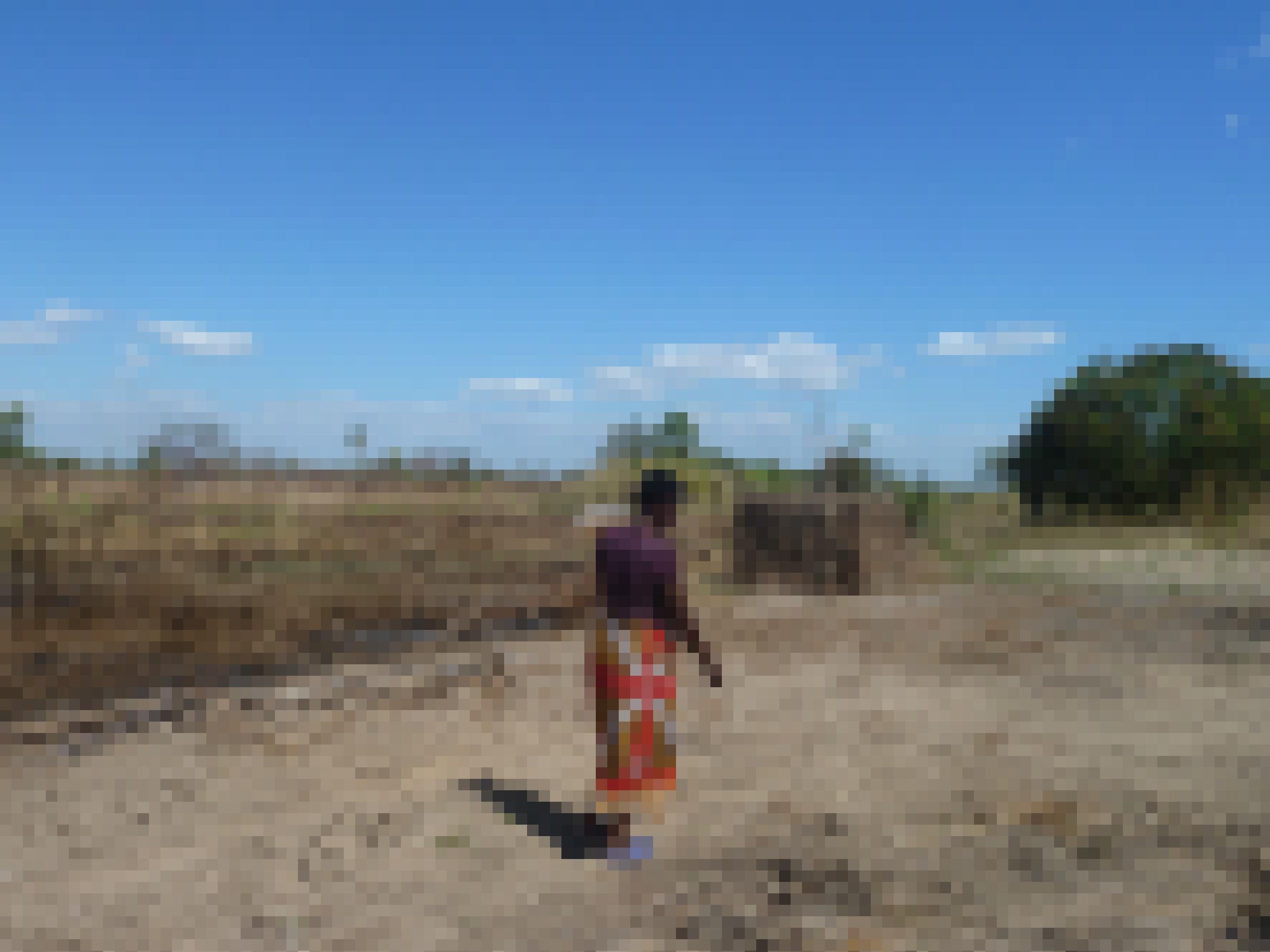 Das Bild zeigt eine Kleinbaeuerin in Mosambik, die an ihrem Feld vorbeigeht – Zyklon Idai hat es 2019 komplett vernichtet. An einen Anbau ist nicht zu denken