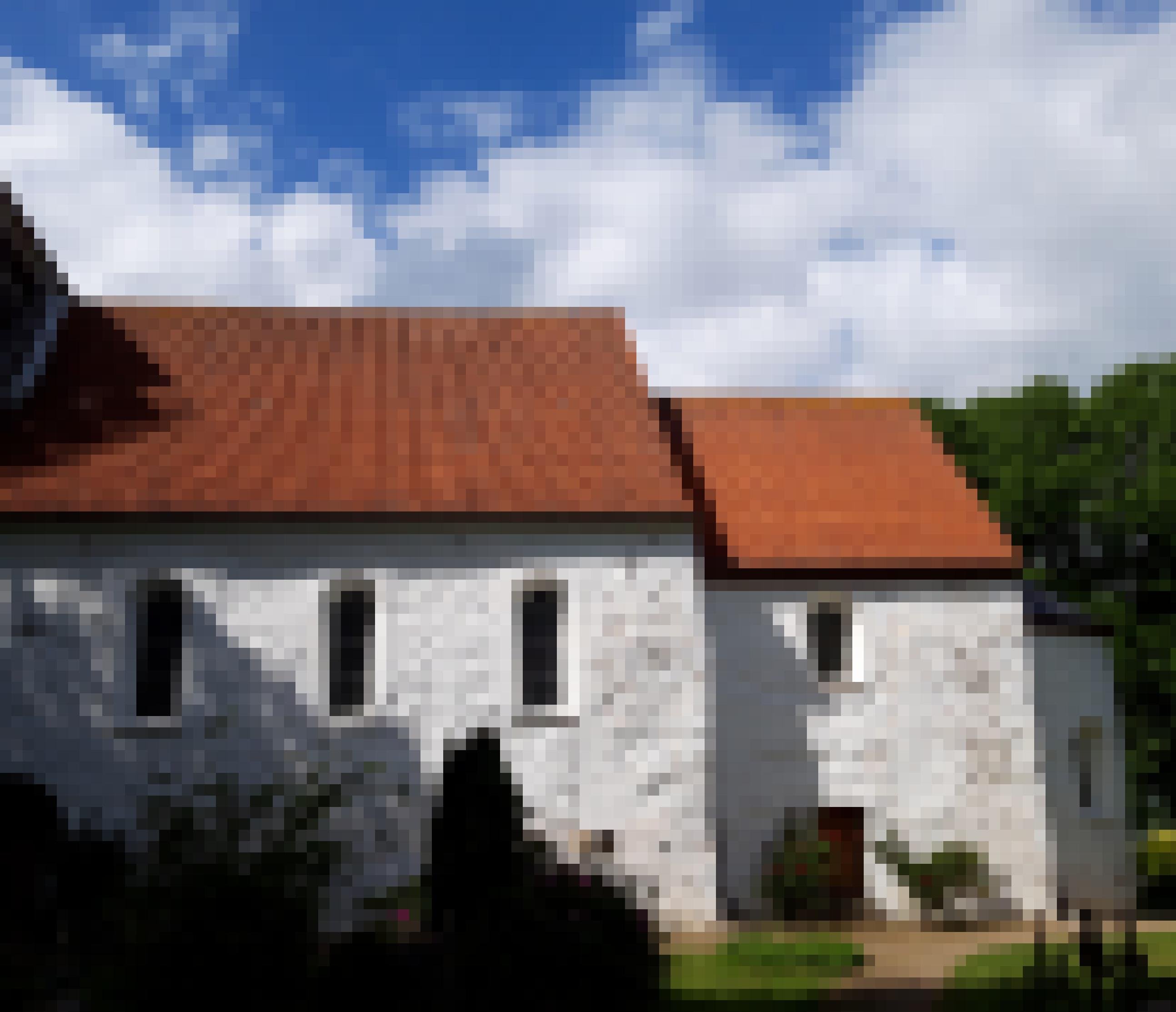 Spätromanische dunkle Fensterbögen in einer gleißend weiß gestrichenen Kirchfassade.