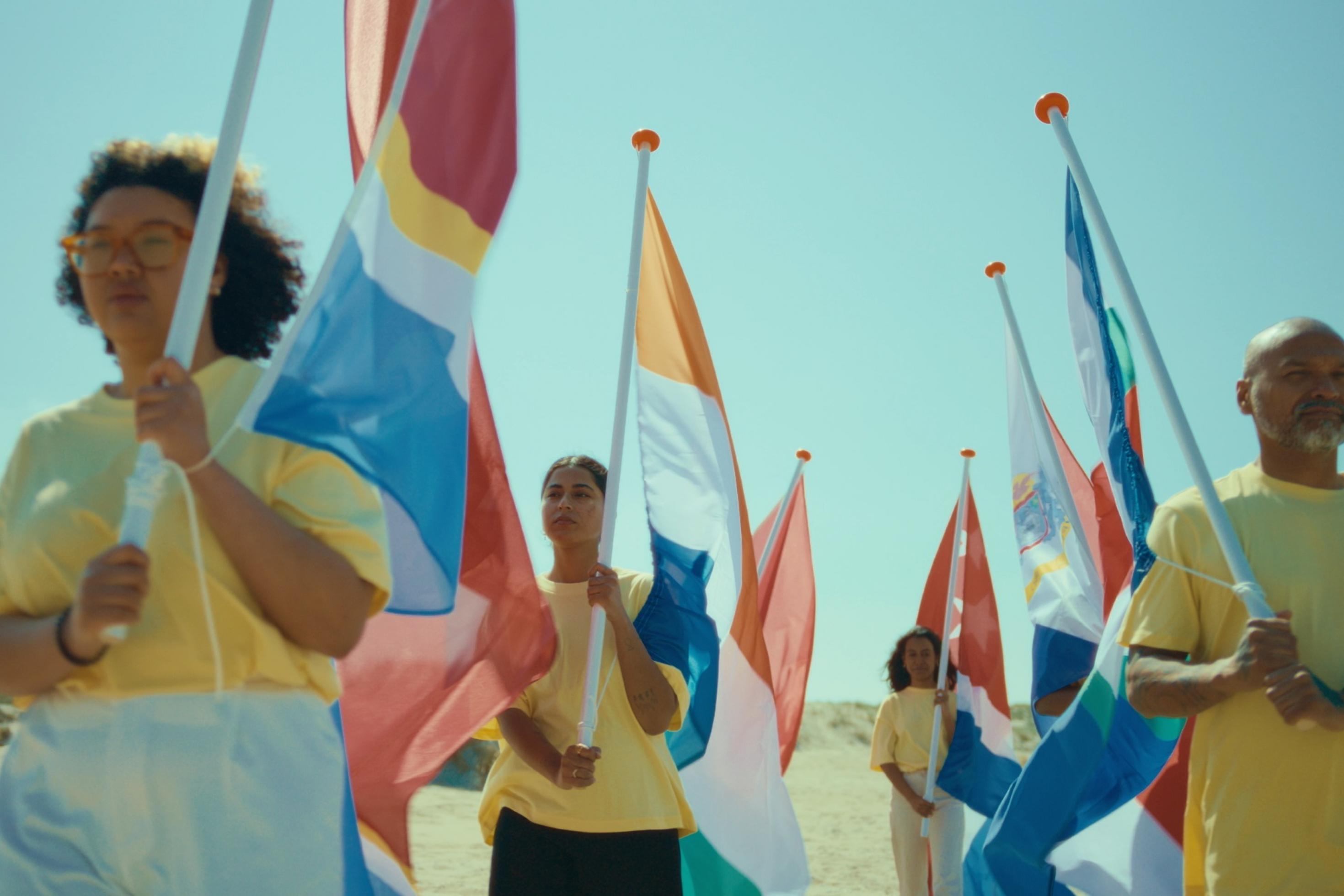 Prozession von Männer und Frauen unterschiedlicher Hautfarbe, die unterschiedliche Fahnen tragen.Fahnen