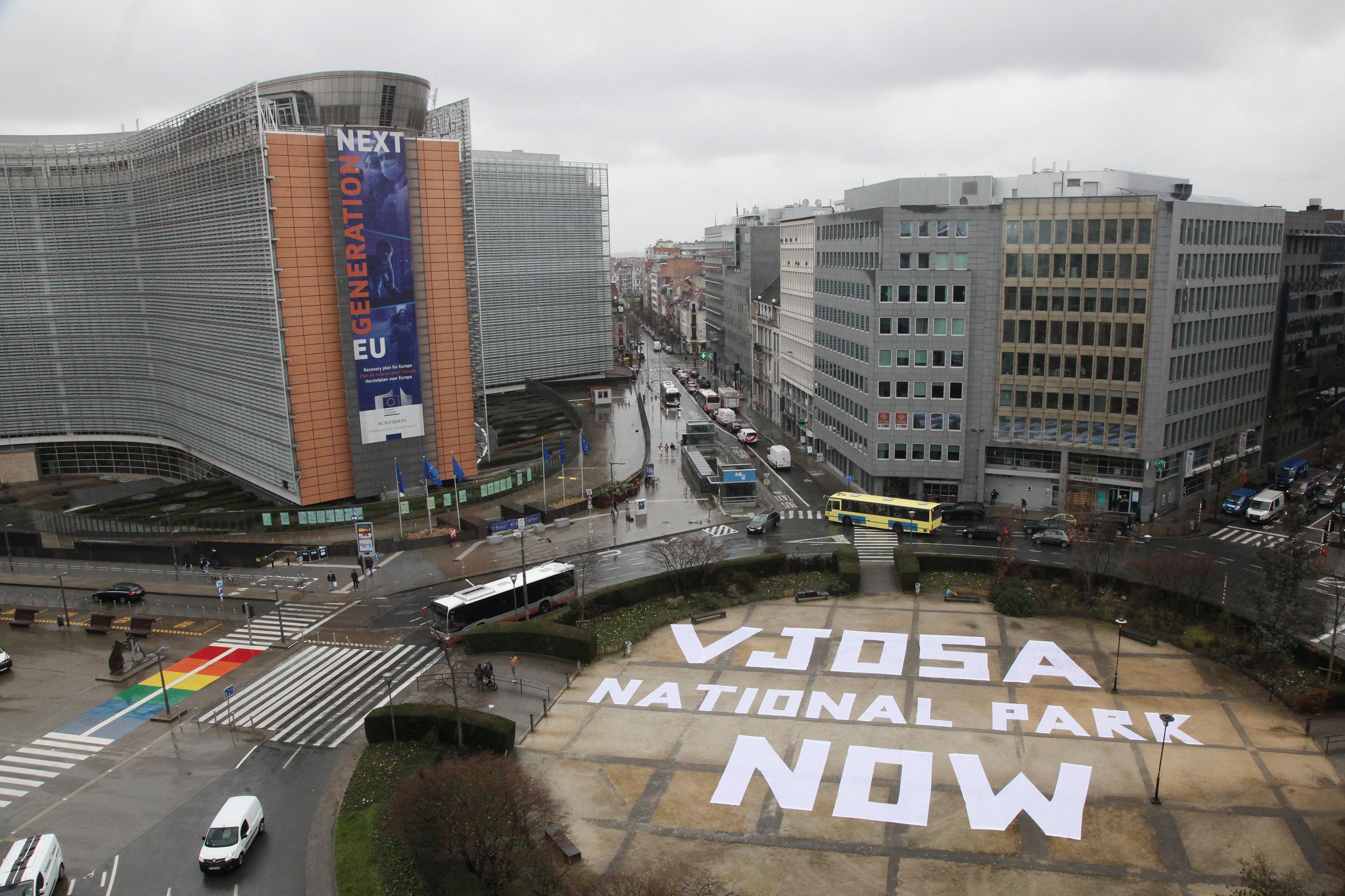 Großer weißer Schriftzug vor großem EU-Gebäude in Brüssel.