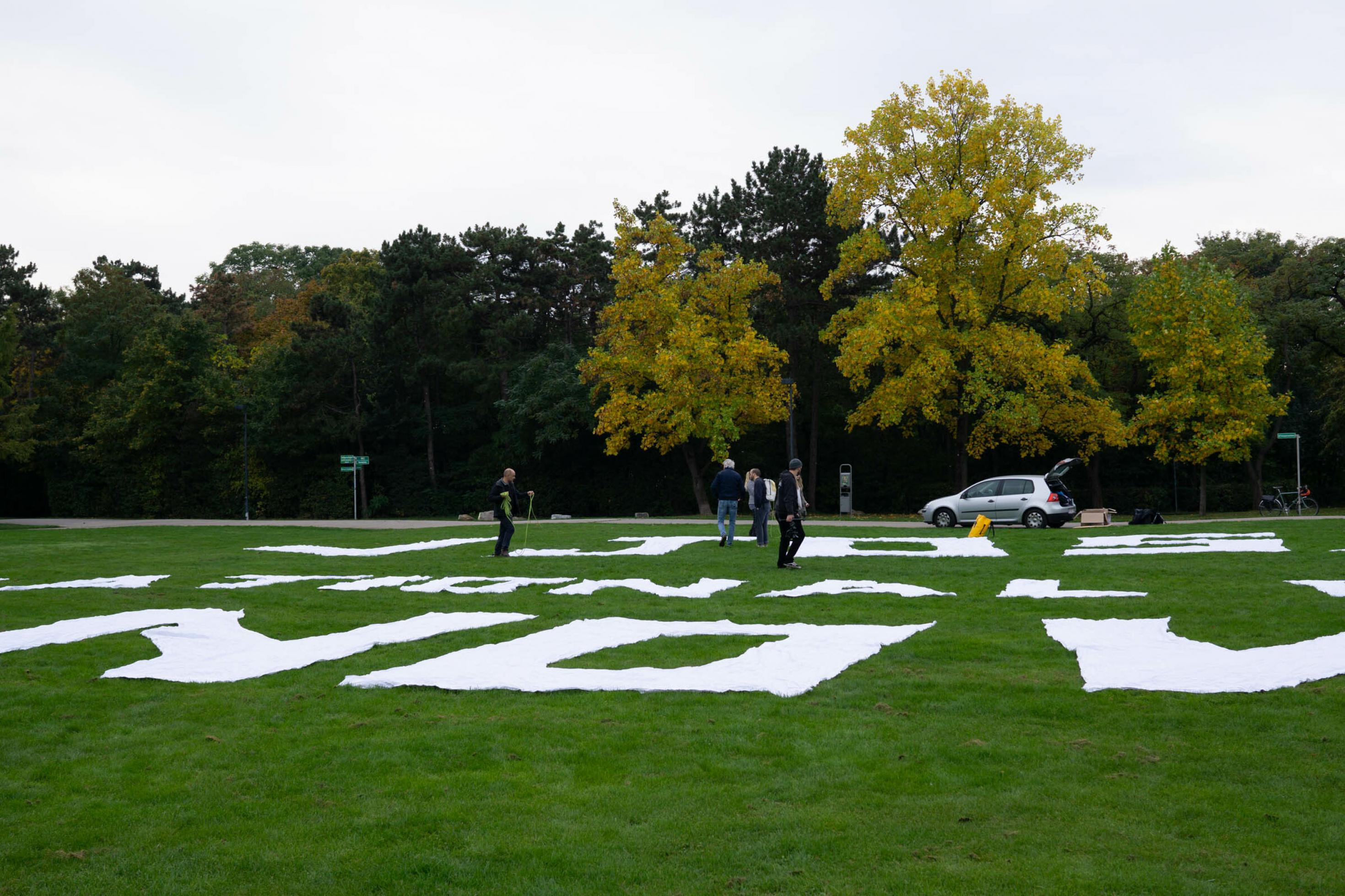 Wiese im Park, weiße Buchstaben aus Stoff auflegen.