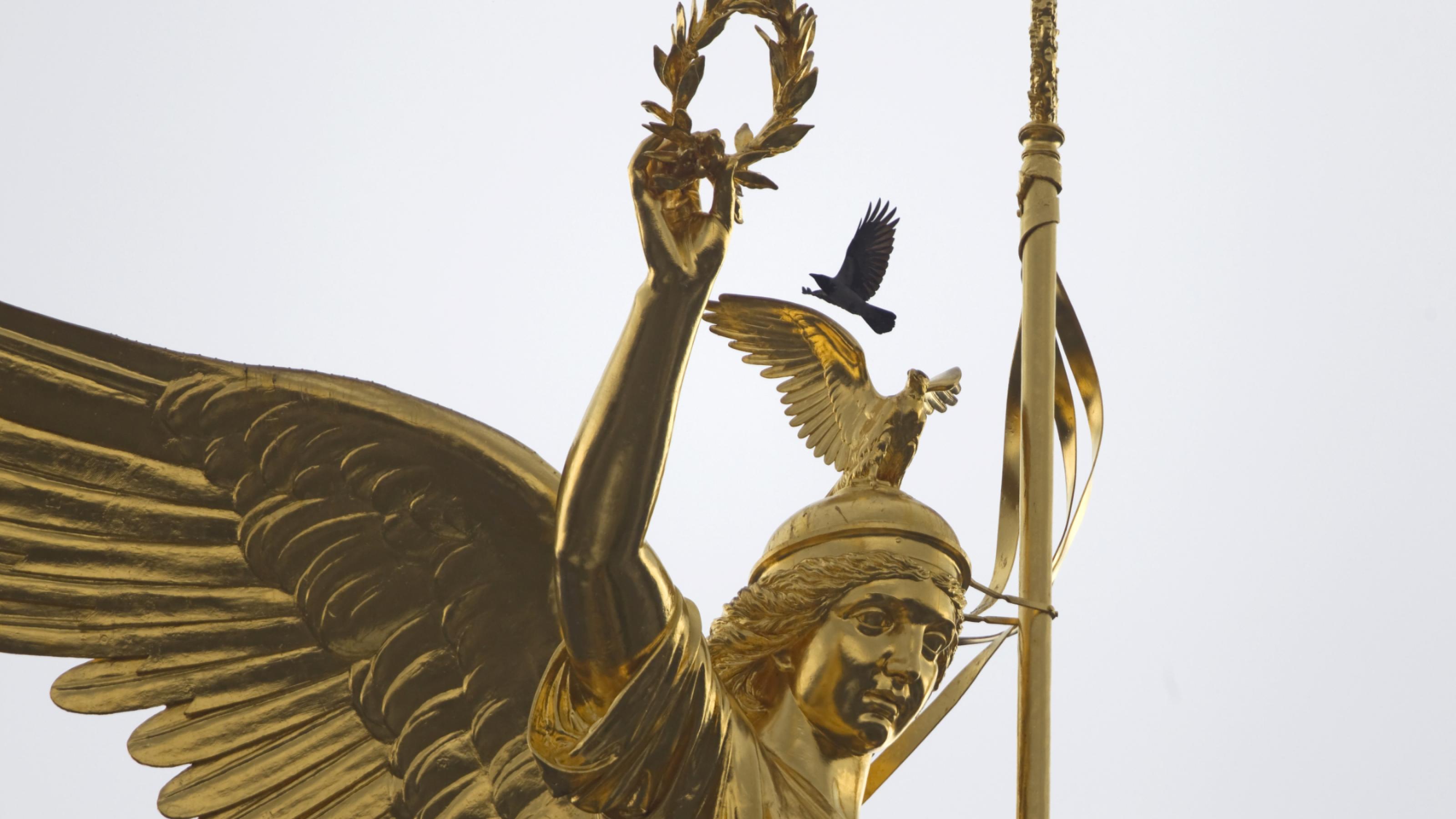 Eine Nebelkrähe landet auf der Bronzestatue der Siegessäule