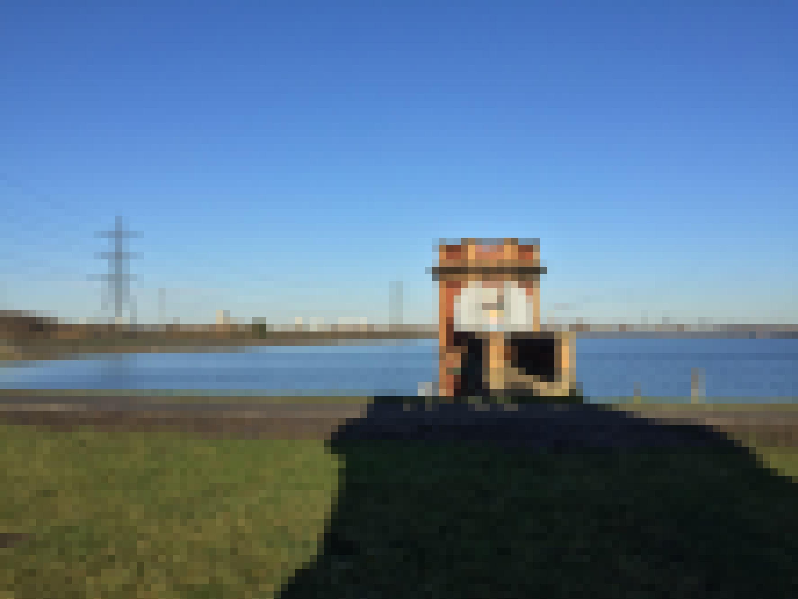 Foto eines Sees. Ein kleiner Backsteinturm steht am Ufer.