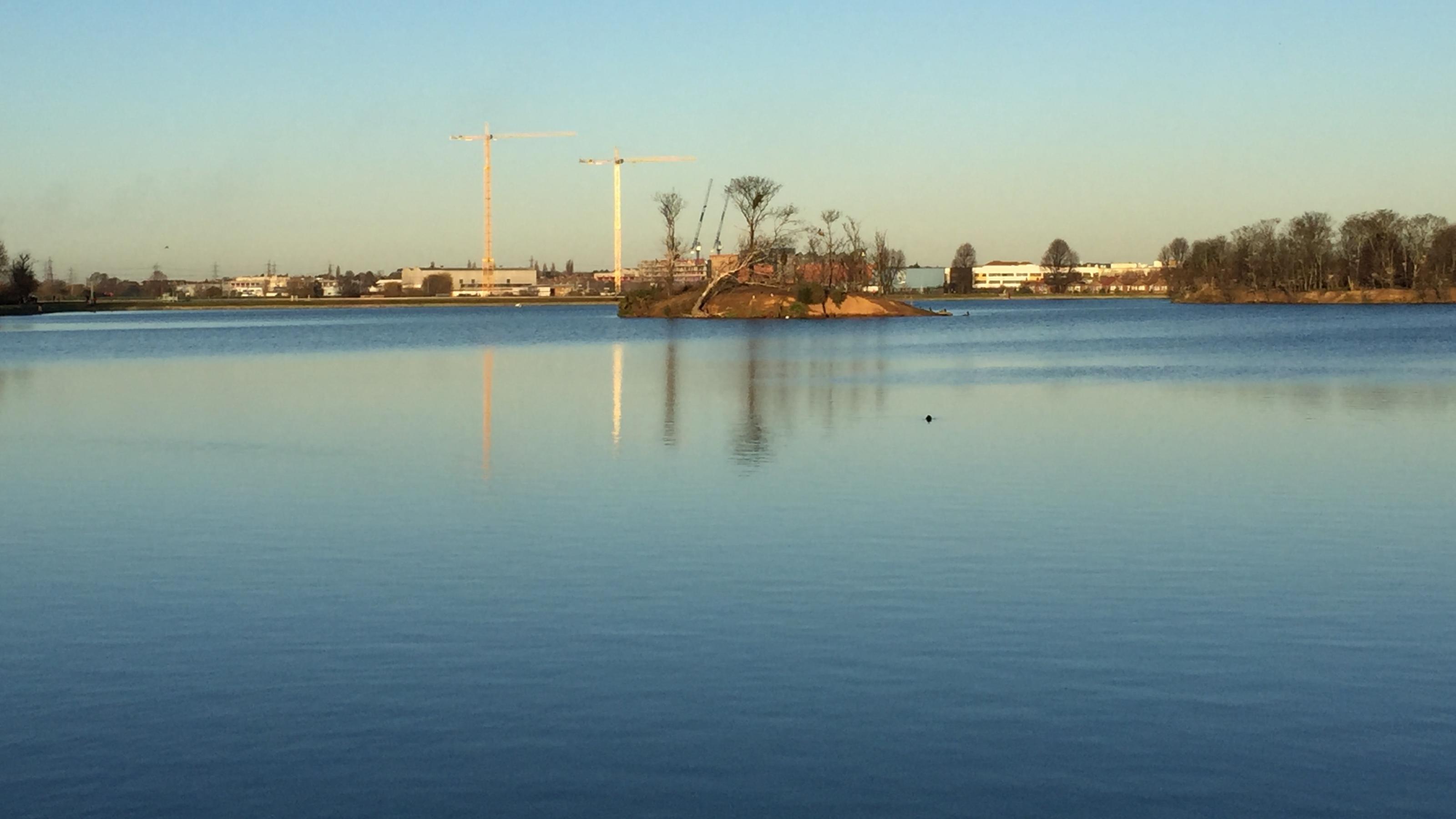 Foto eines Sees. In der Mitte des Sees befindet sich eine kleine Insel.