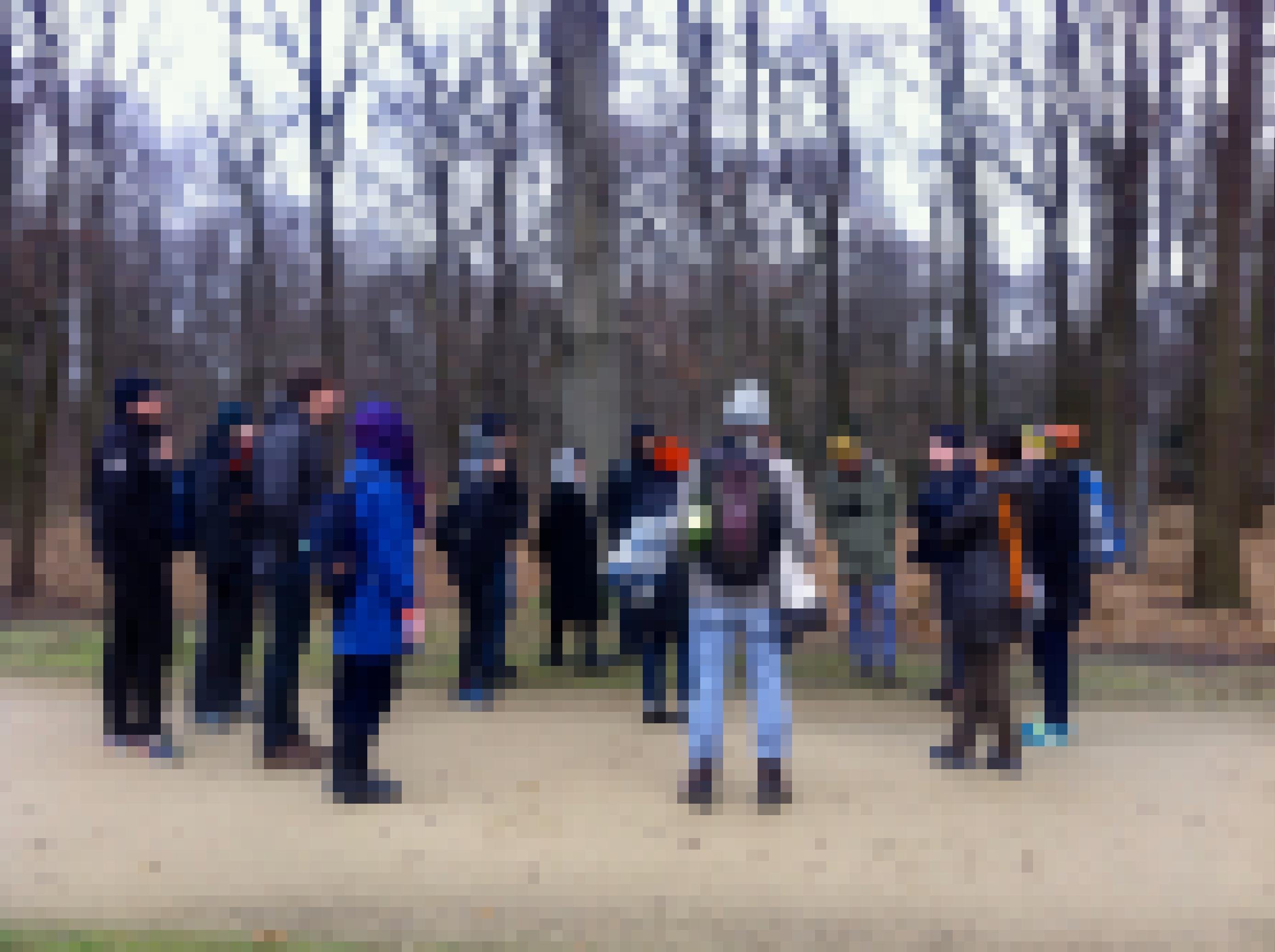 Eine Gruppe Menschen steht auf einem Weg in einem Wald.