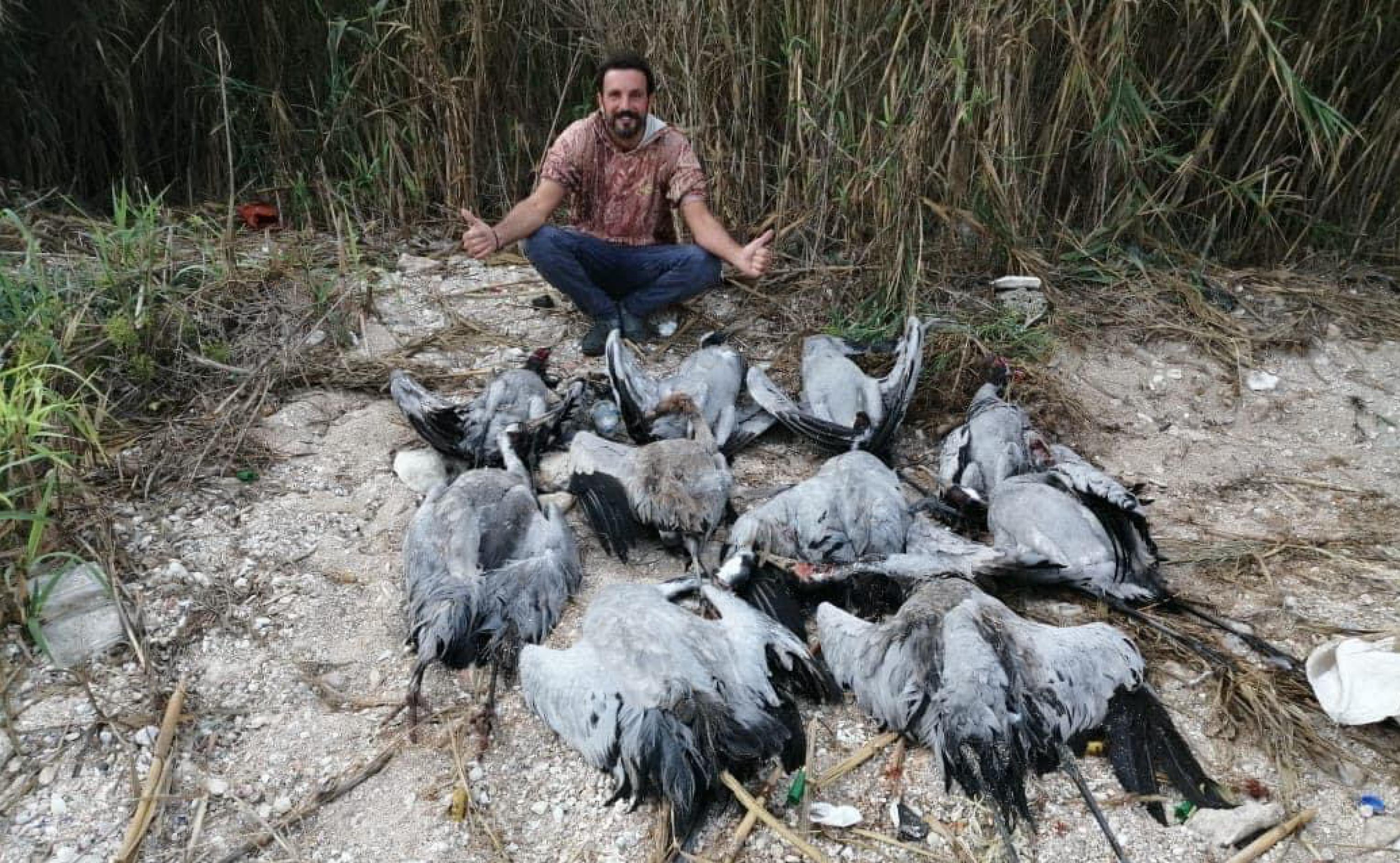 Ein Vogelwilderer hält stolz vier tote Kraniche in die Luft