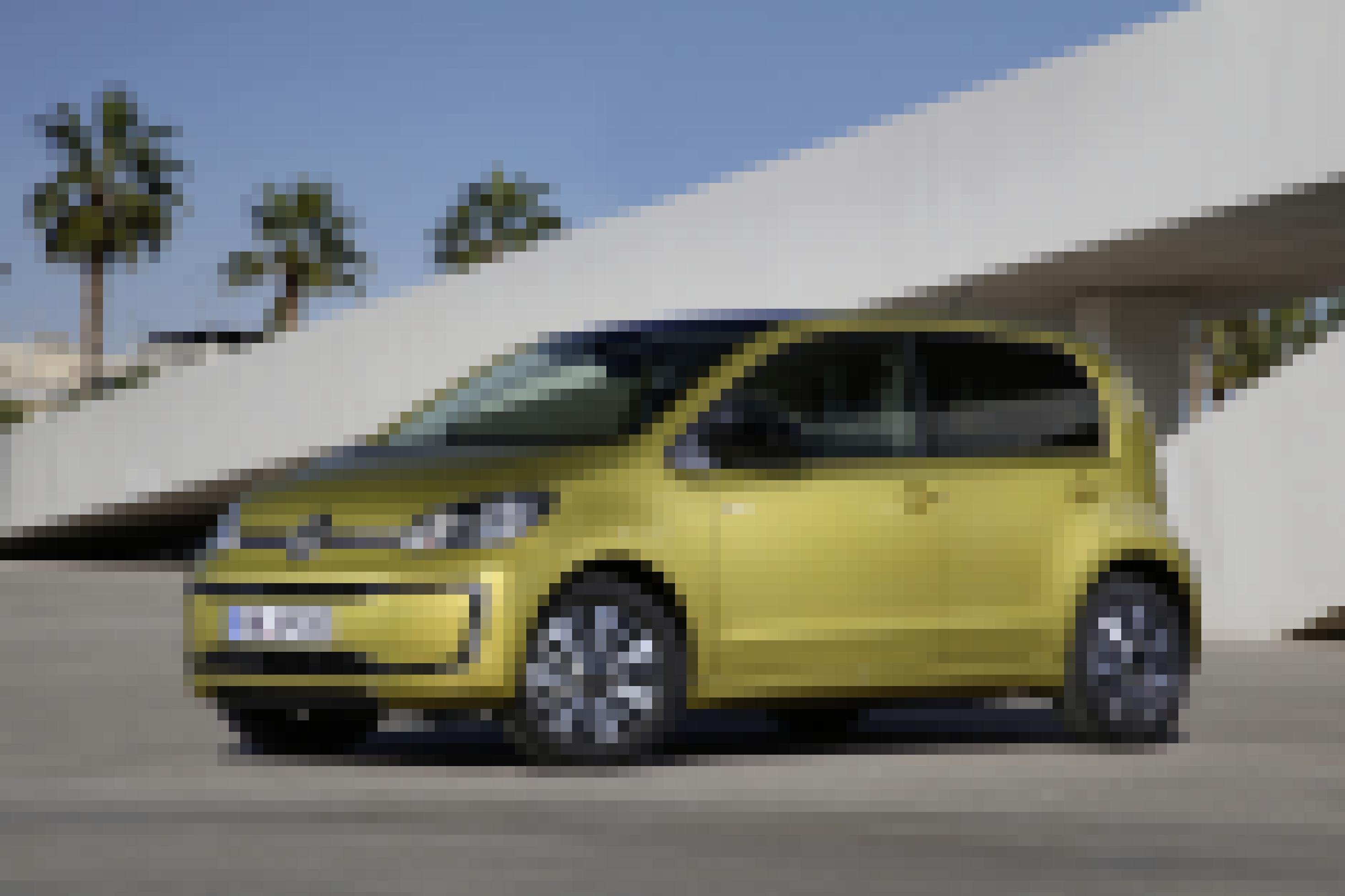 Ein elektrischer Kleinwagen parkt vor einer Beton-Struktur. Im Hintergrund sind Palmen zu sehen.