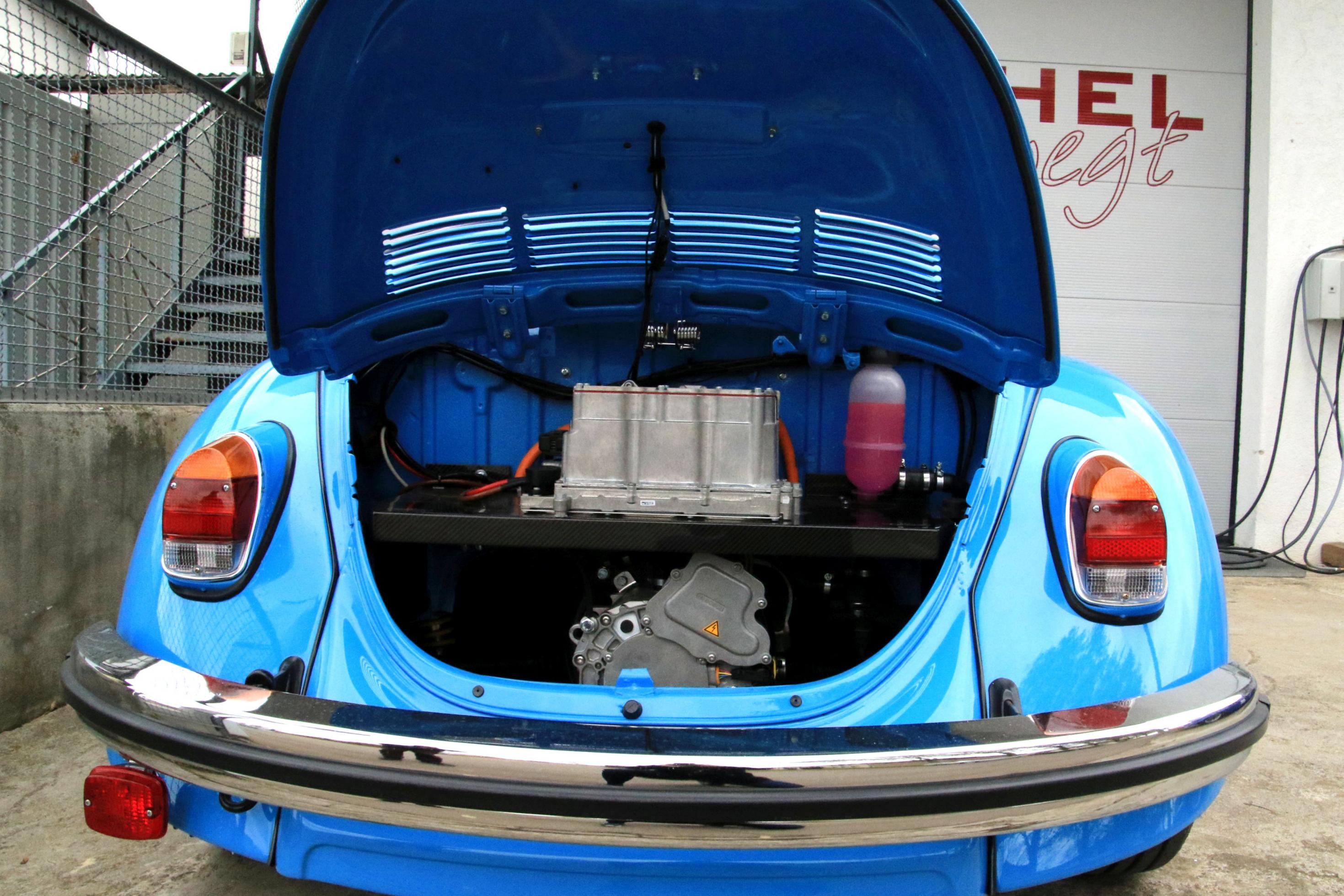 Die Heckklappe eines VW Käfer ist geöffnet. Im Inneren ein Elektromotor.