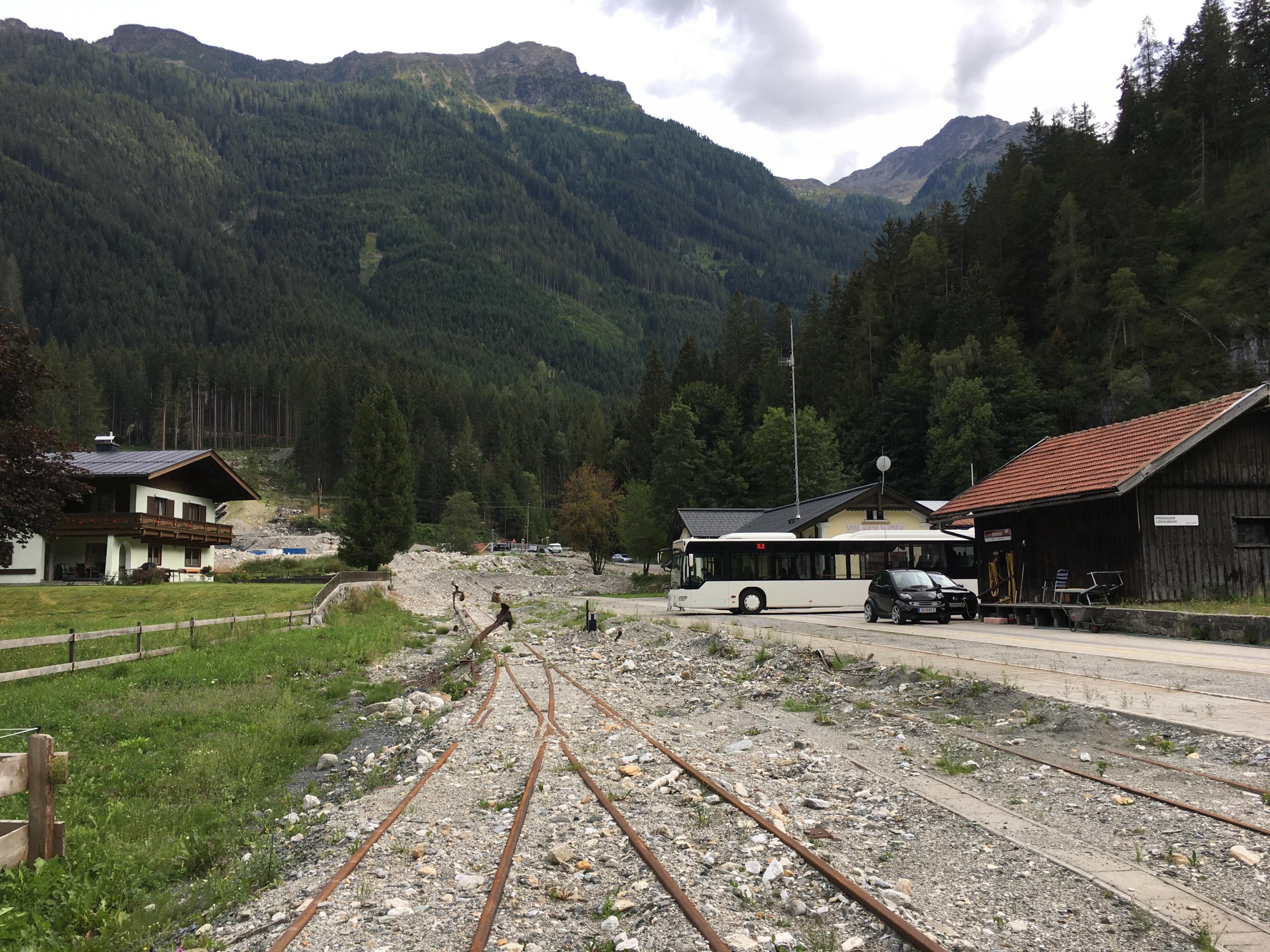 Gleisanlage mit Schotter und verbogenen Weichen, im Hintergrund ein Berg mit einem Graben