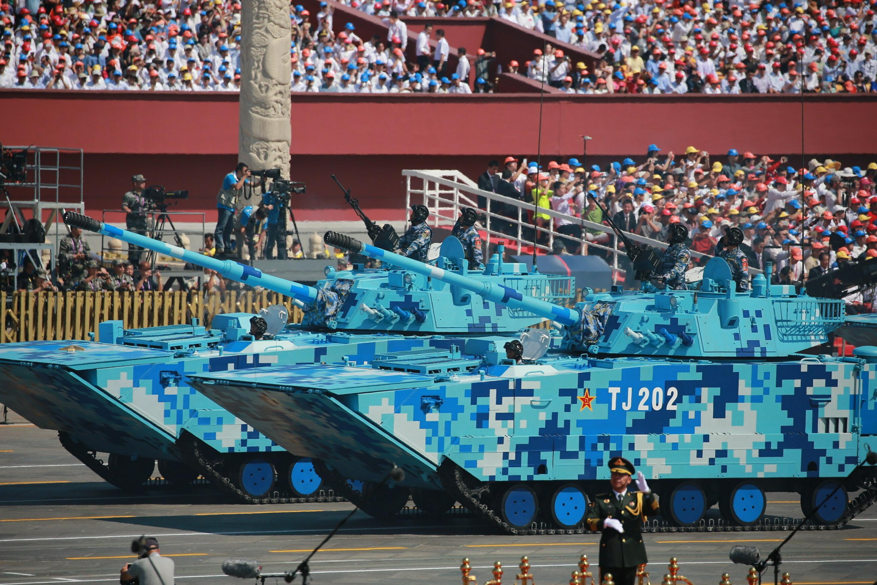 Zwei Panzer bei einer Militärparade, die nicht wie üblich grün, sondern in einem blauen Tarnmuster angestrichen sind.